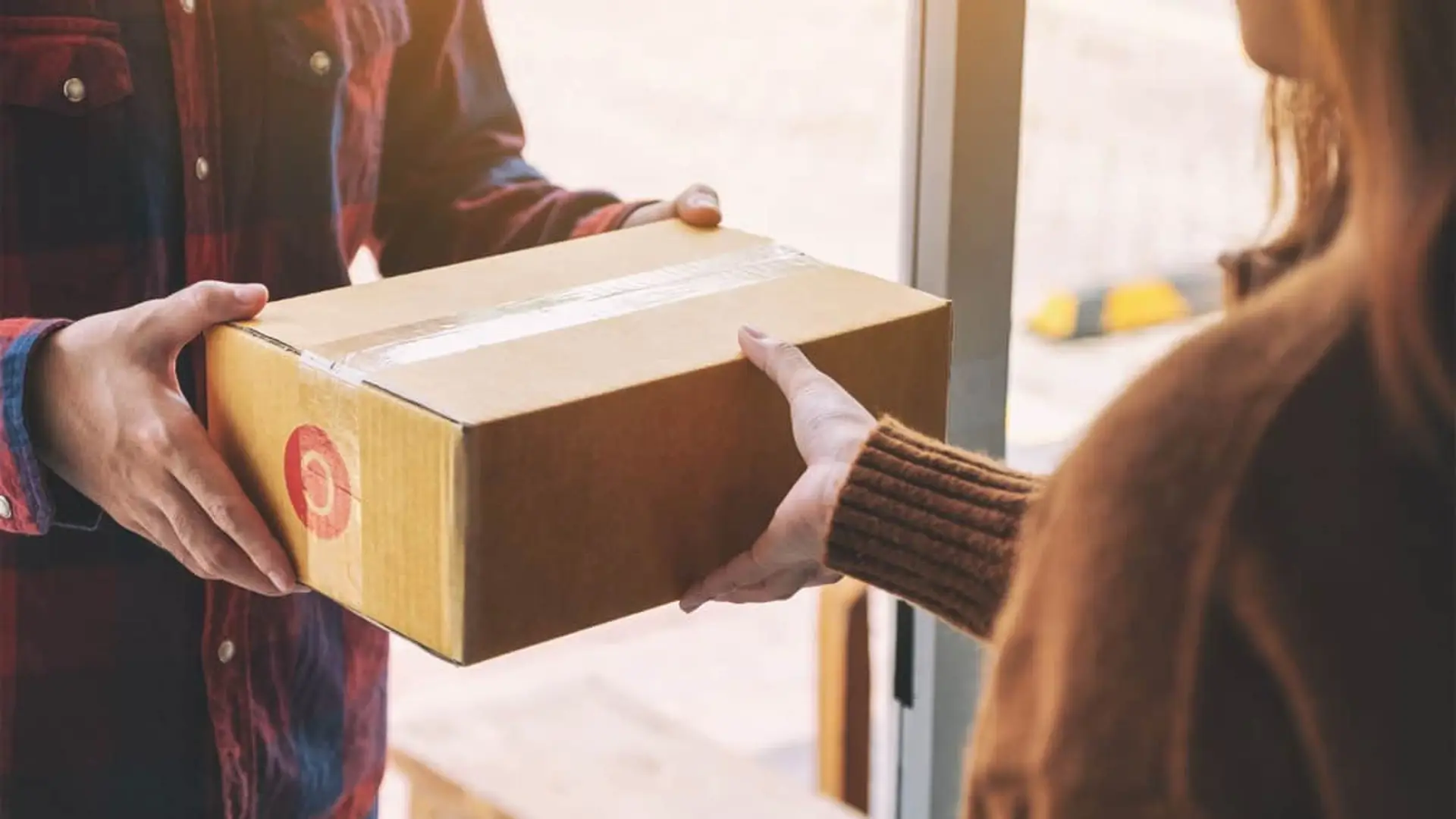 Ni regalo ni error de Amazon, Temu o AliExpress: el paquete que no esperabas esta Navidad puede ser una estafa Repartidor entregando caja de cartón a una mujer en la puerta de su casa por envío de ecommerce.