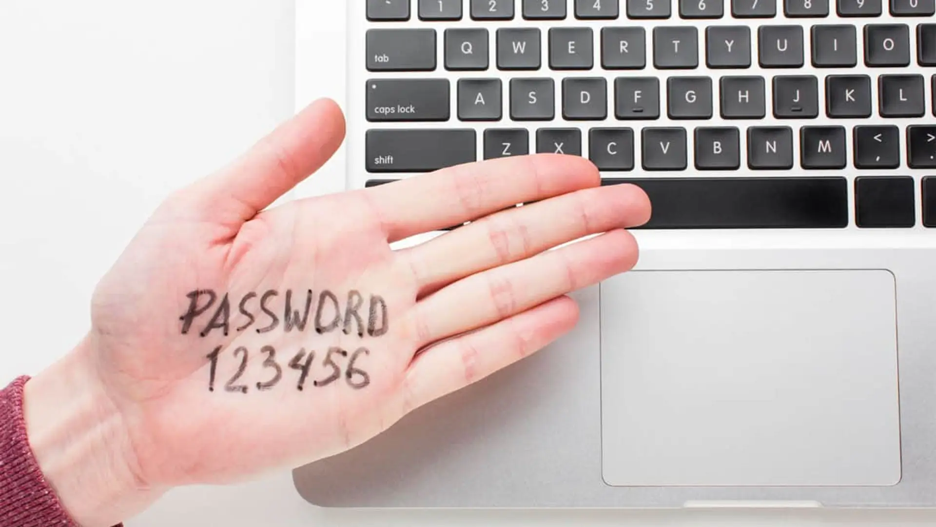 Mano con la contraseña Password 123456 sobre un teclado, representando el uso de claves poco seguras.