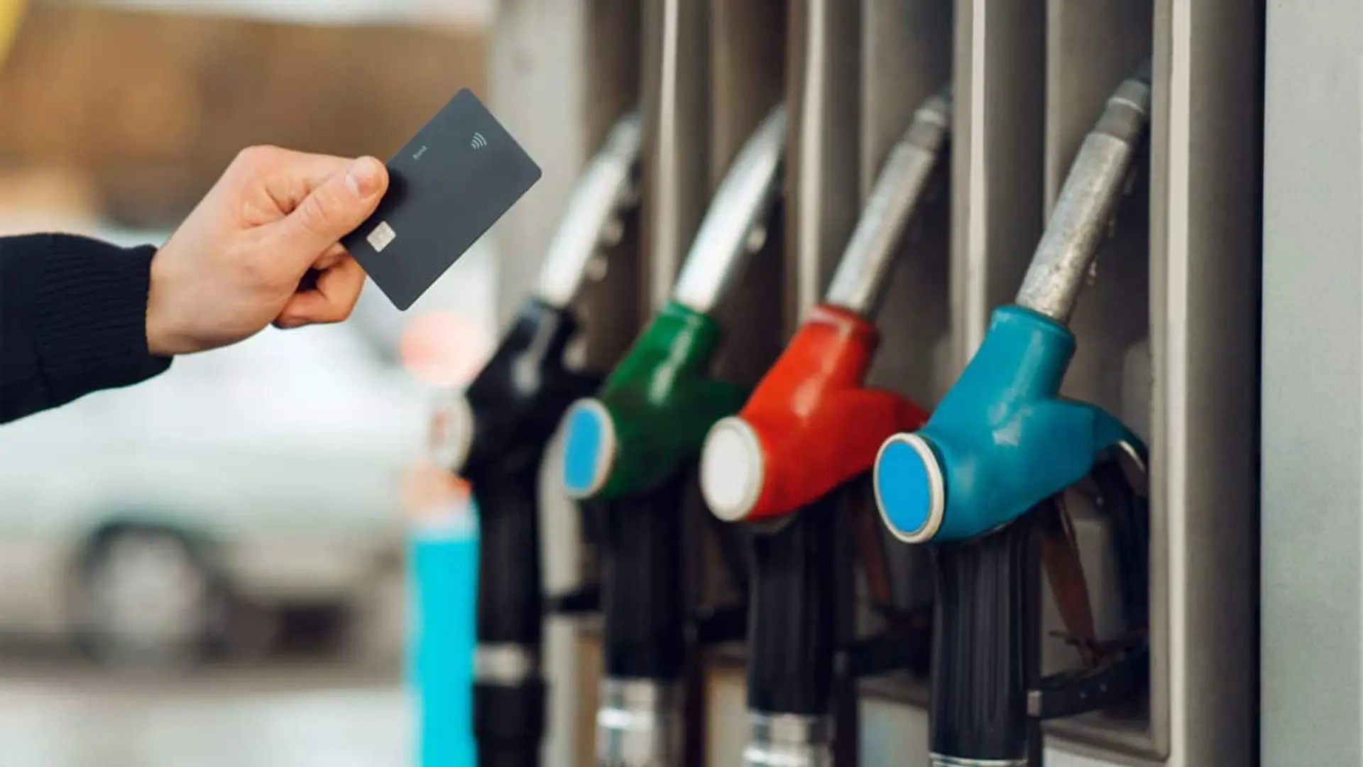Te copian el PIN y clonan tu tarjeta en la gasolinera: cinco claves para evitar la estafa Mano sosteniendo una tarjeta bancaria frente a varios surtidores de gasolina