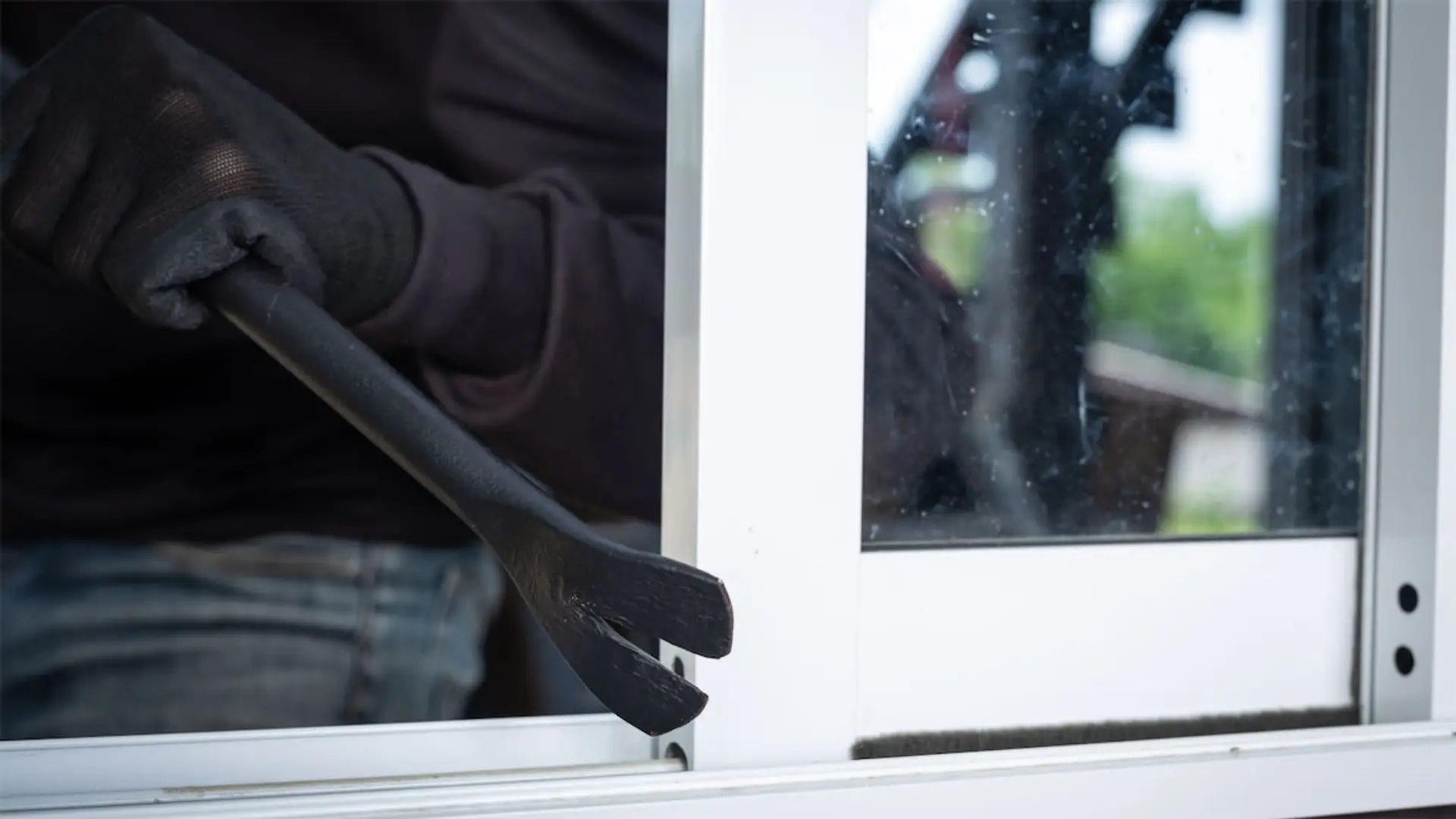 Ni lunes ni viernes: este es el día que los ladrones eligen para robar Ladrón con guantes usando una palanca para forzar y abrir una ventana corredera para entrar a robar en una vivienda.