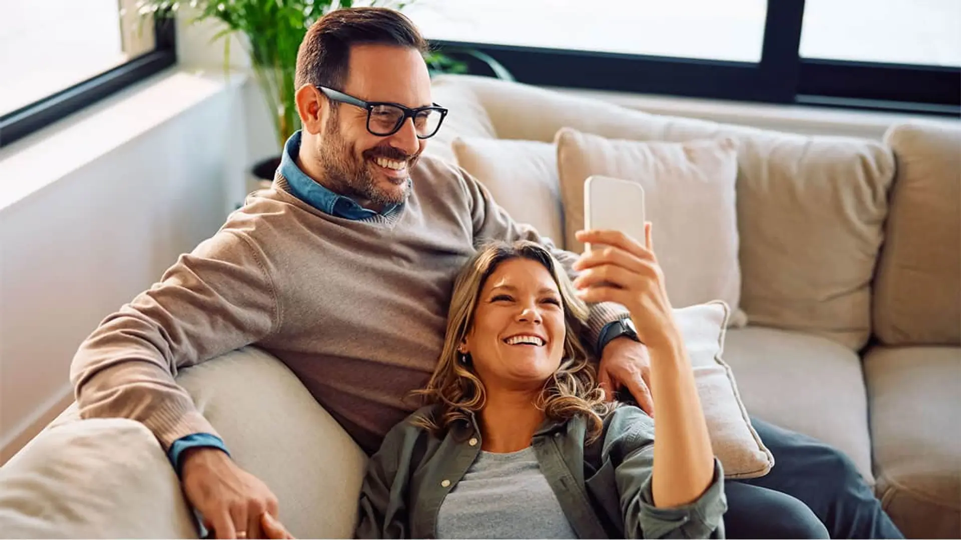 Segurma recupera su mejor oferta: así puedes contratar su alarma por menos de 20 euros al mes Pareja feliz en el sofá de su casa, disfrutando de la tranquilidad de un hogar protegido con una alarma de seguridad.