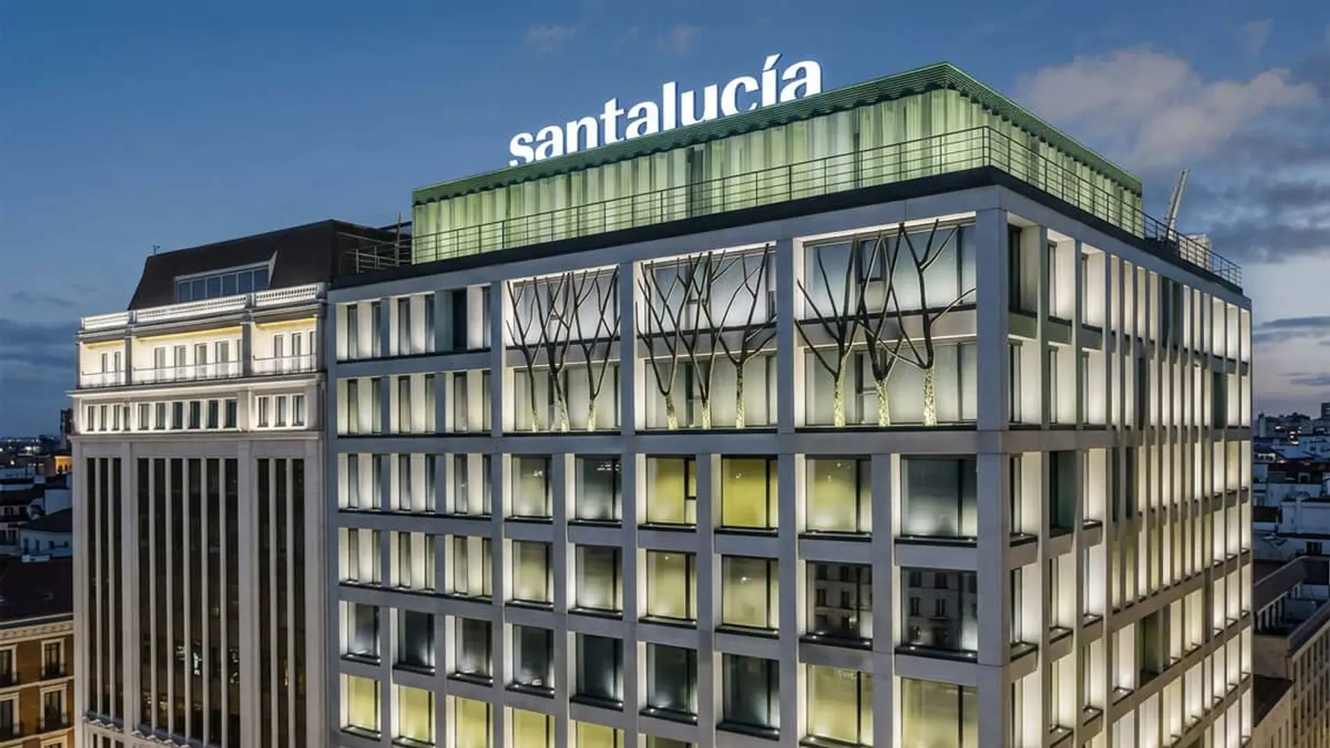Fachada de la sede de Santalucía Seguros con su logotipo iluminado en la azotea del edificio moderno.