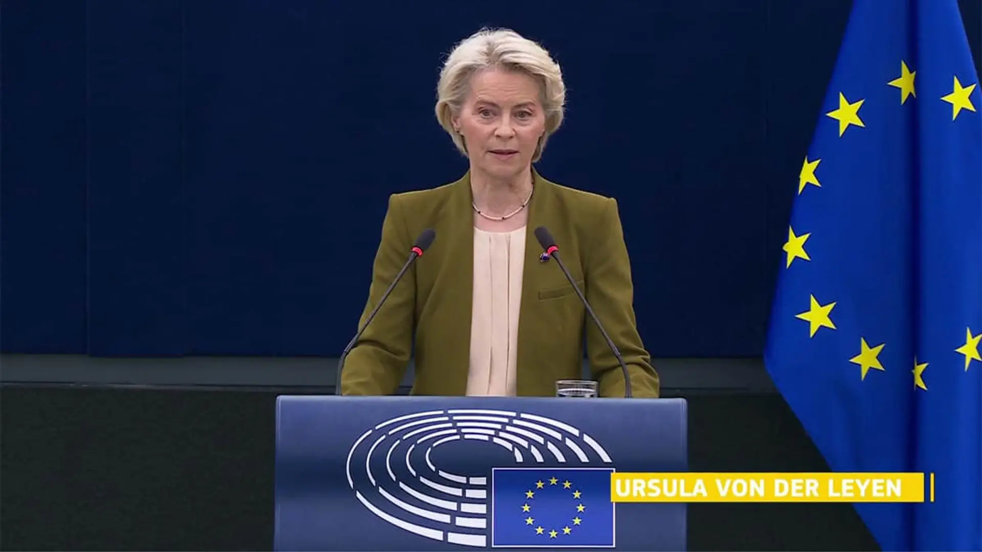 Ursula von der Leyen interviniendo en el Parlamento Europeo con la bandera de la Unión Europea de fondo.