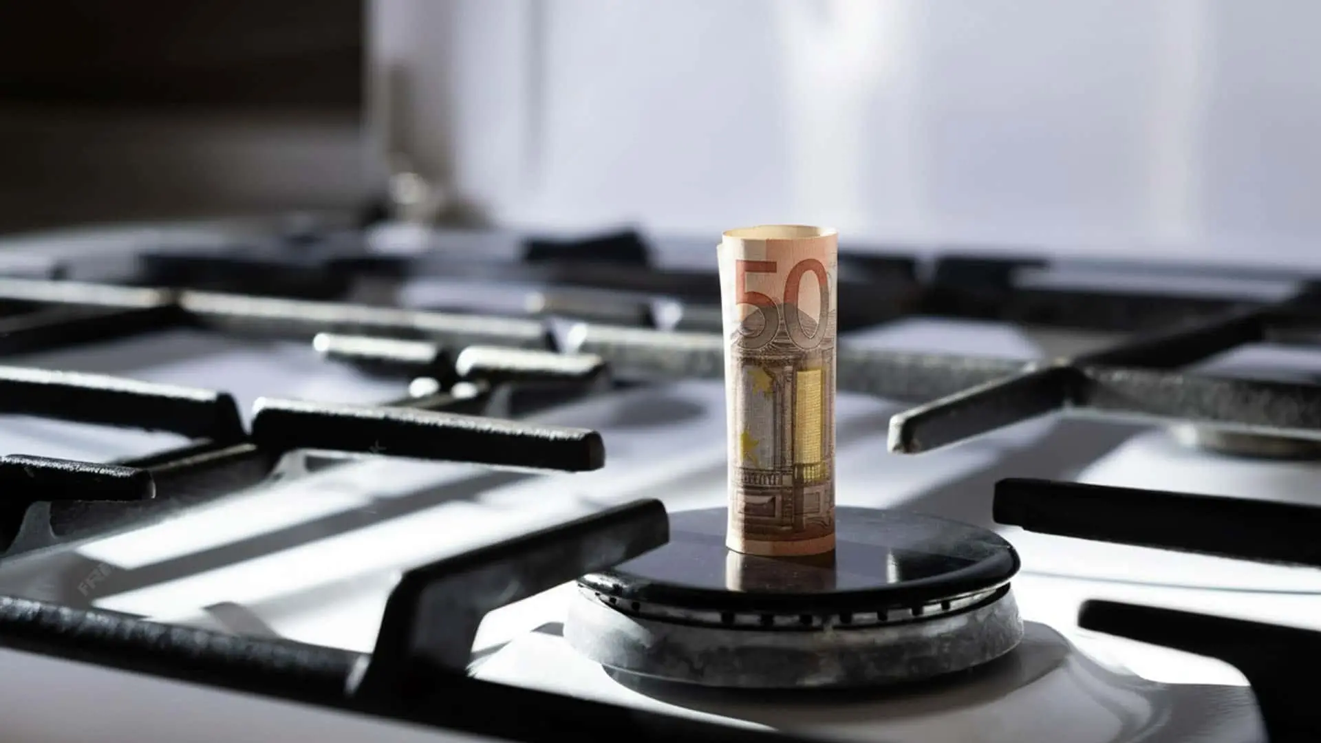 Billete de 50 euros colocado sobre un fogón de cocina de gas.