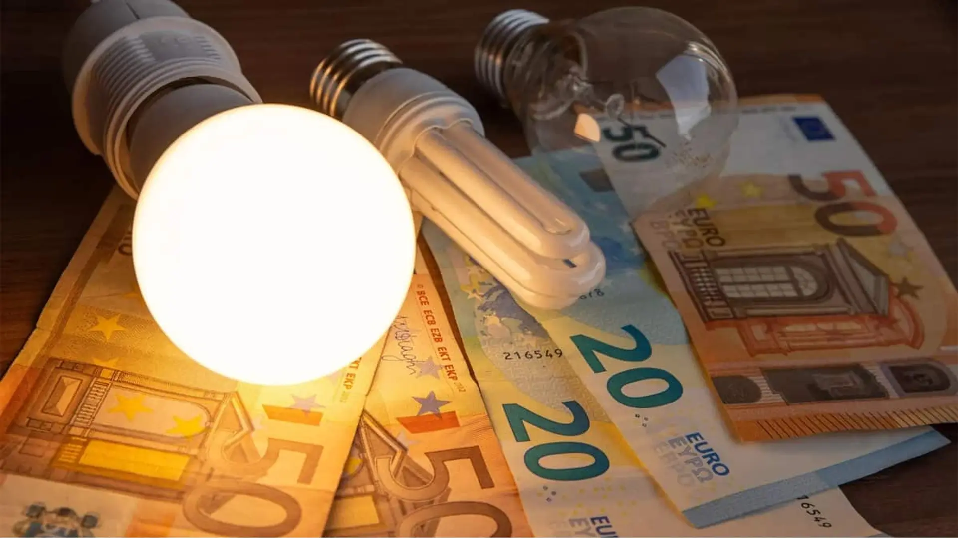 Bombillas encendidas y apagadas sobre billetes de euro, simbolizando el coste de la electricidad y el consumo energético.
