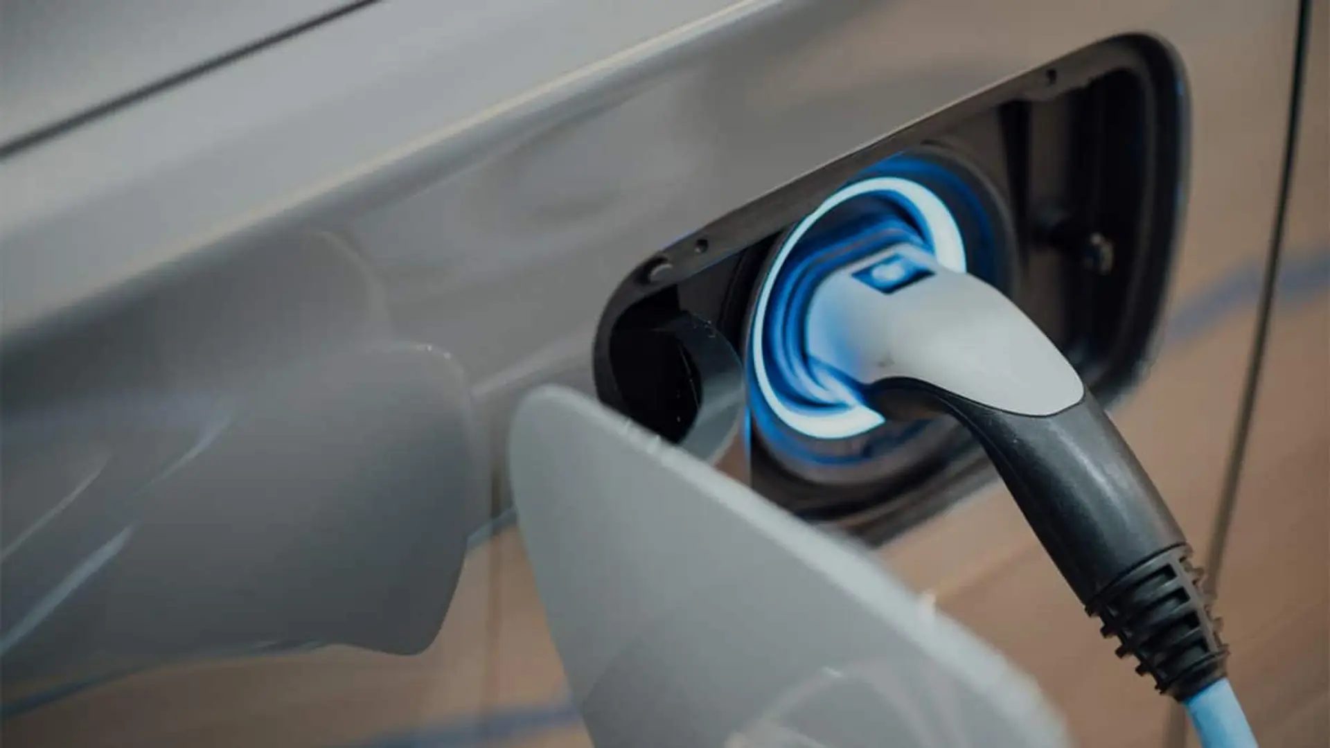 Detalle de un conector enchufado en la toma de carga de un coche eléctrico.