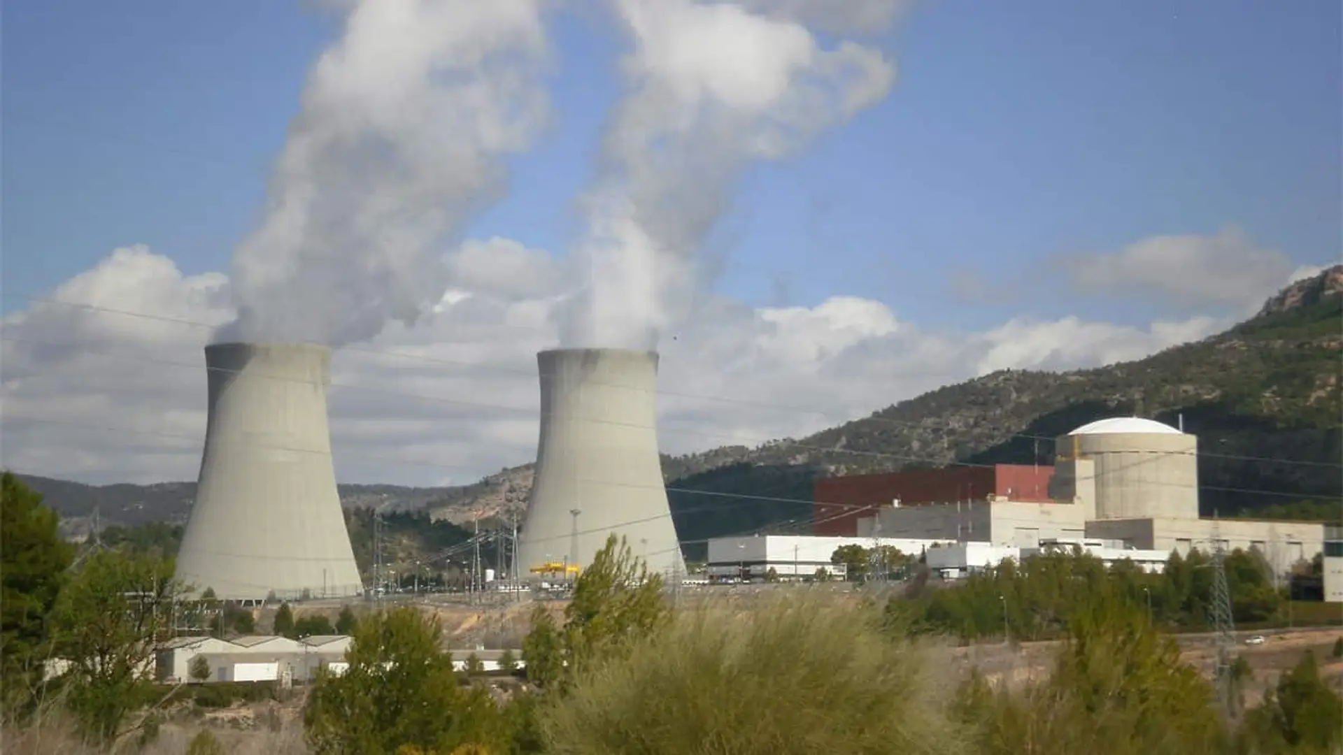 Revertir el cierre de nucleares más allá de Almaraz, una decisión con limitaciones Vista general de la central nuclear de Cofrentes, con sus torres de refrigeración emitiendo vapor entre montañas.