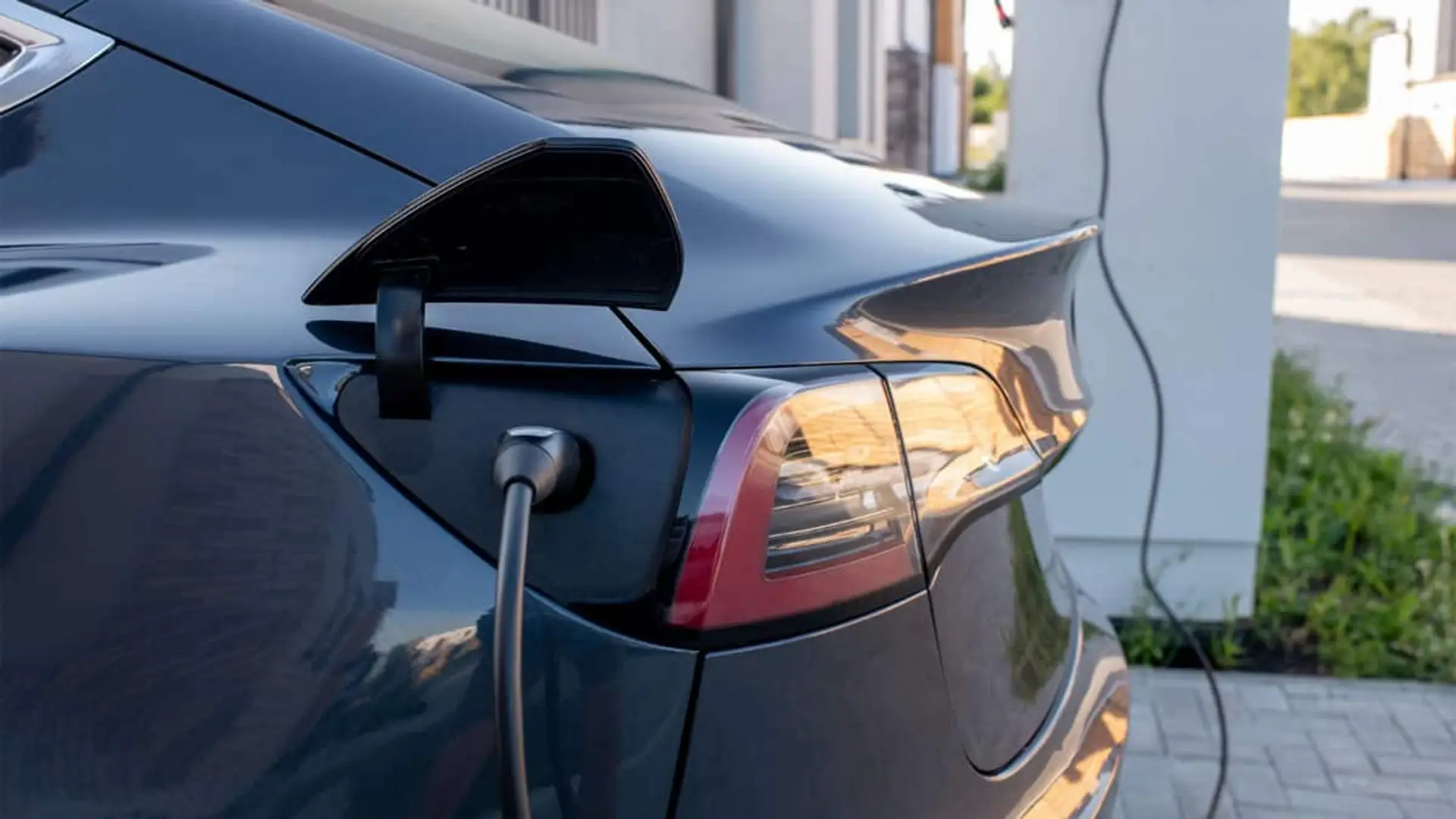Coche eléctrico conectado a un punto de recarga, con el cable enchufado en la parte trasera del vehículo.