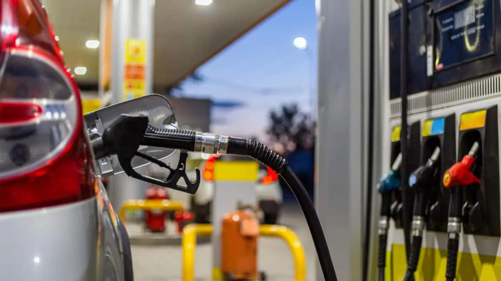 Coche repostando en una gasolinera con la manguera conectada al depósito