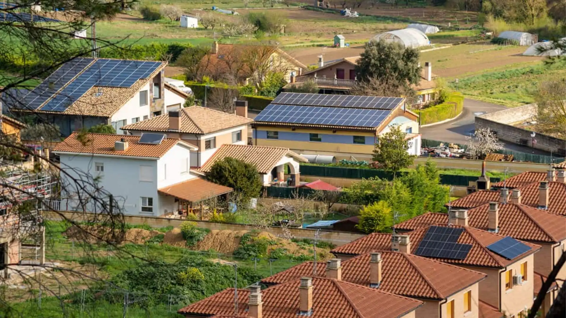Vista aérea de un barrio con viviendas que comparten paneles solares dentro de una comunidad energética local.