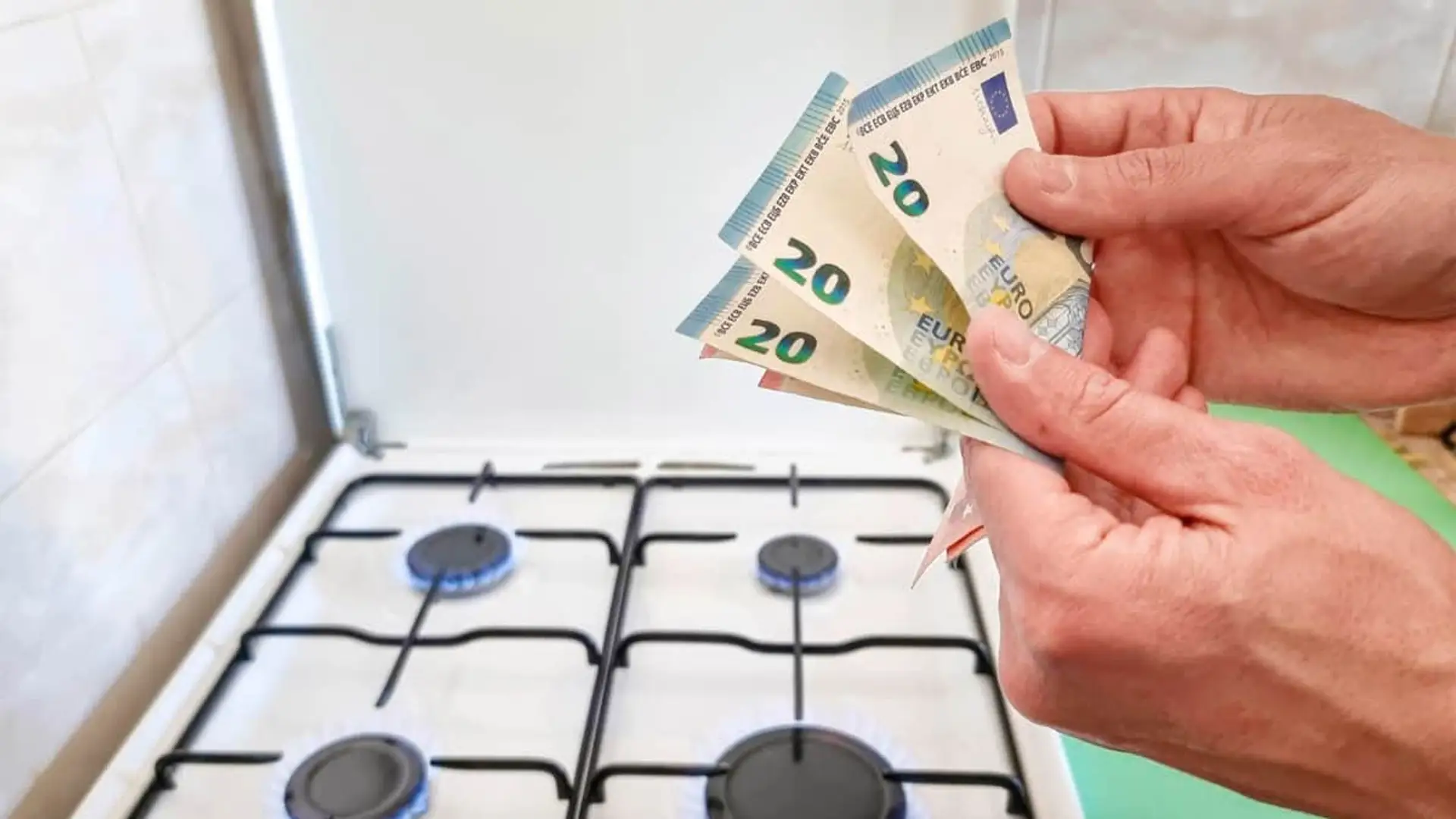 El precio del gas da un respiro en 2026: la TUR baja hasta un 8,7% en enero Manos contando billetes de 20 euros frente a una cocina de gas encendida con llama azul.
