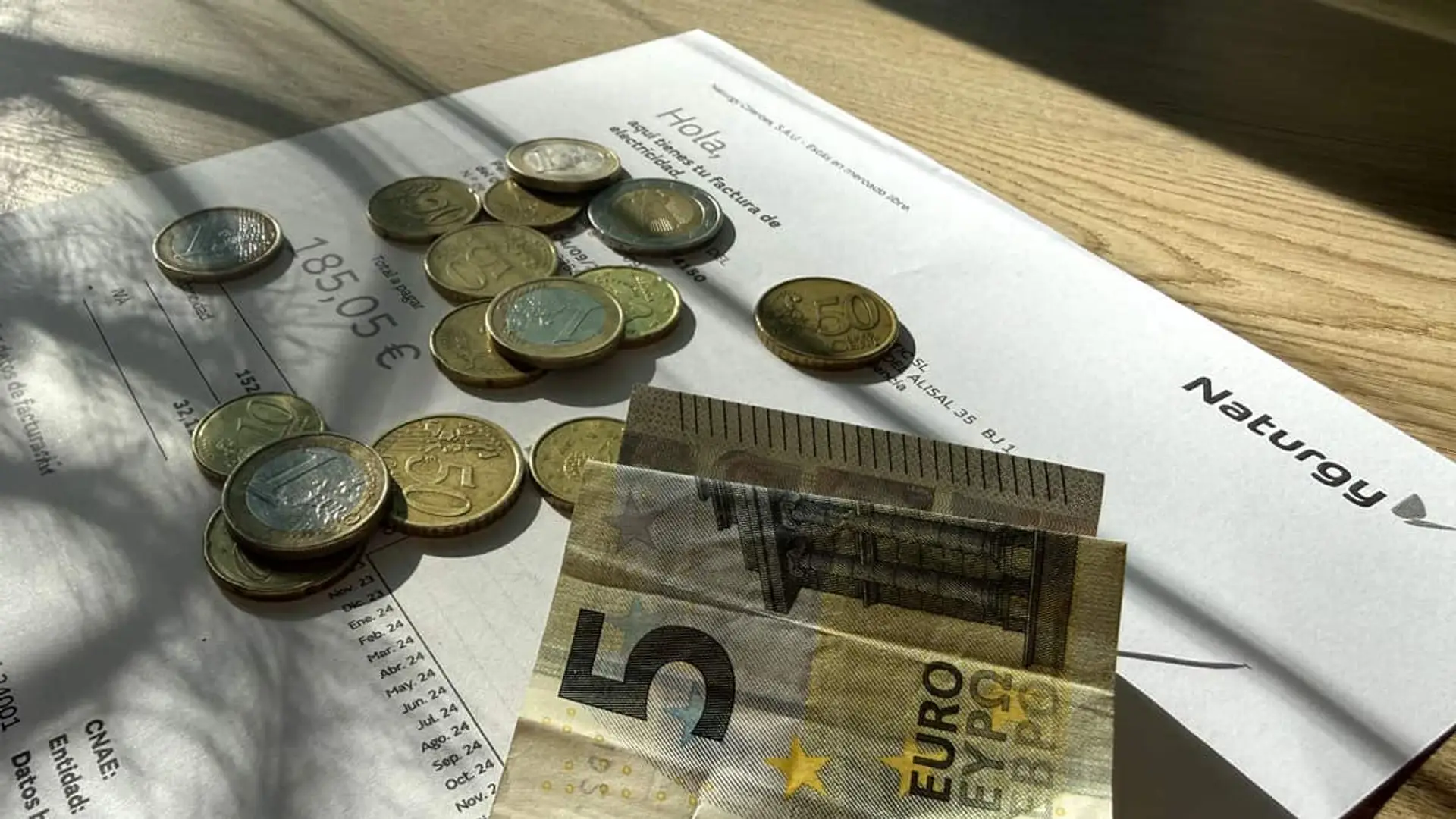 La factura de la luz subirá en 2026: la CNMC y el Gobierno preparan un alza del 5% en los costes fijos Factura de Naturgy sobre una mesa junto a monedas y billetes de euro