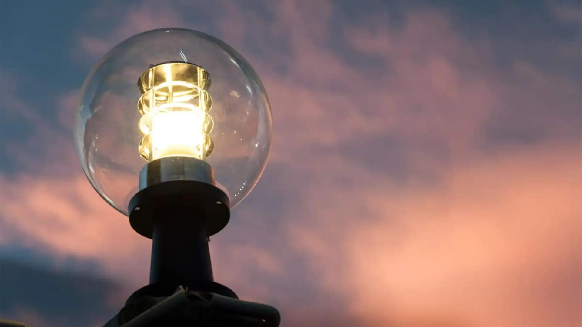 Farola encendida con globo de cristal sobre un cielo al atardecer