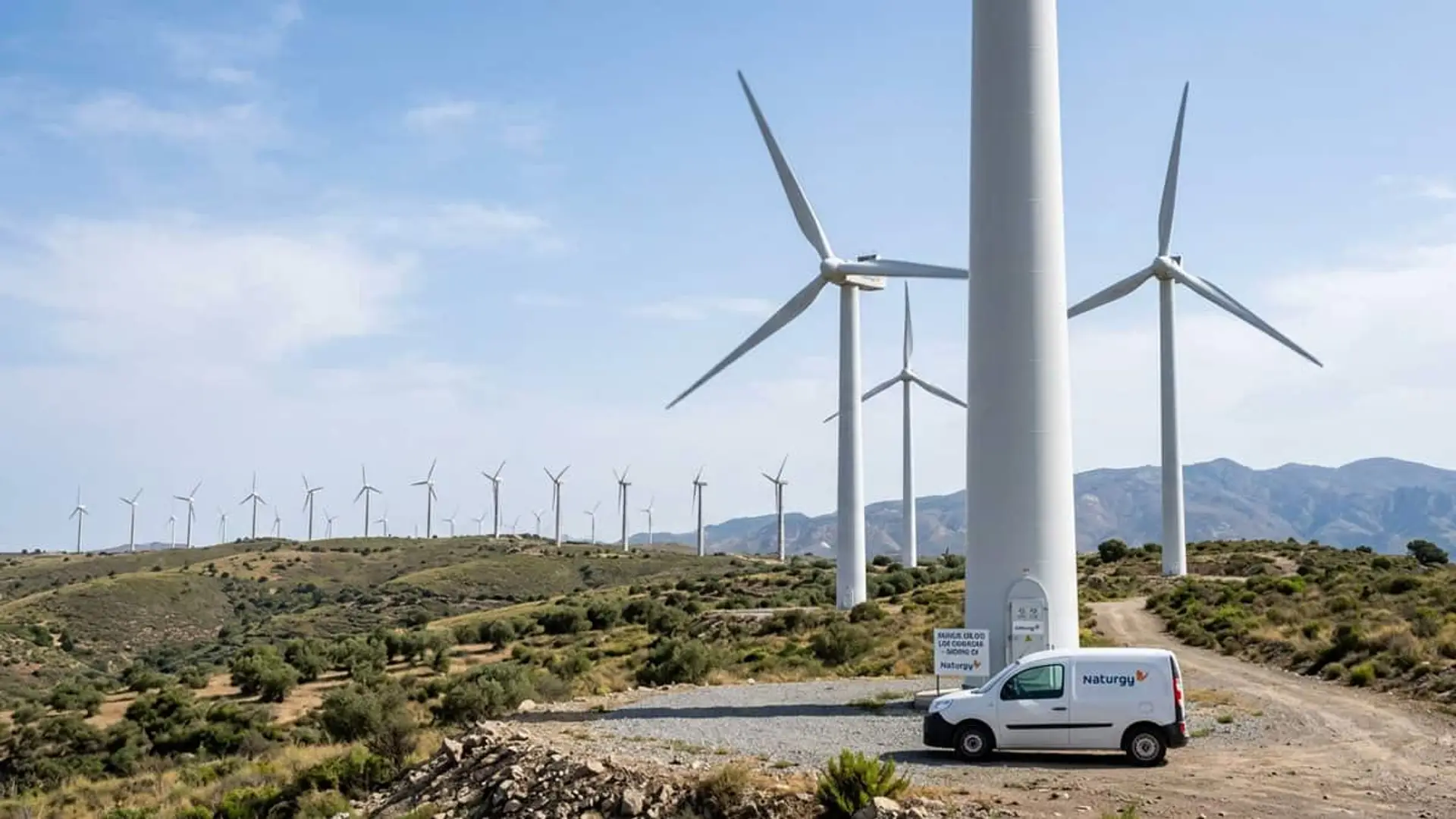 Parque eólico con aerogeneradores de Naturgy y un vehículo de la compañía junto a una de las turbinas
