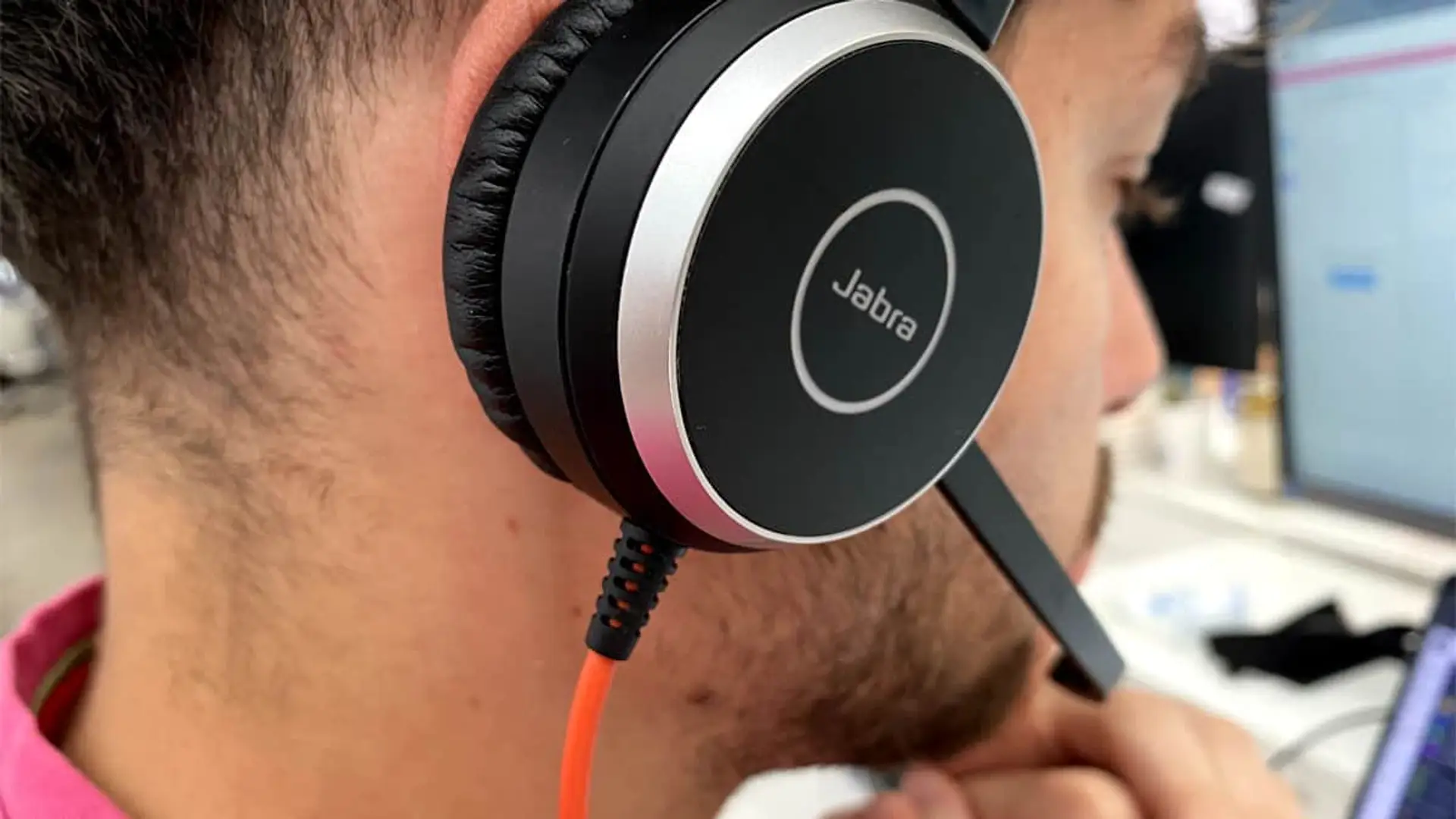 Persona con auriculares de diadema atendiendo una llamada en un centro de atención telefónica.