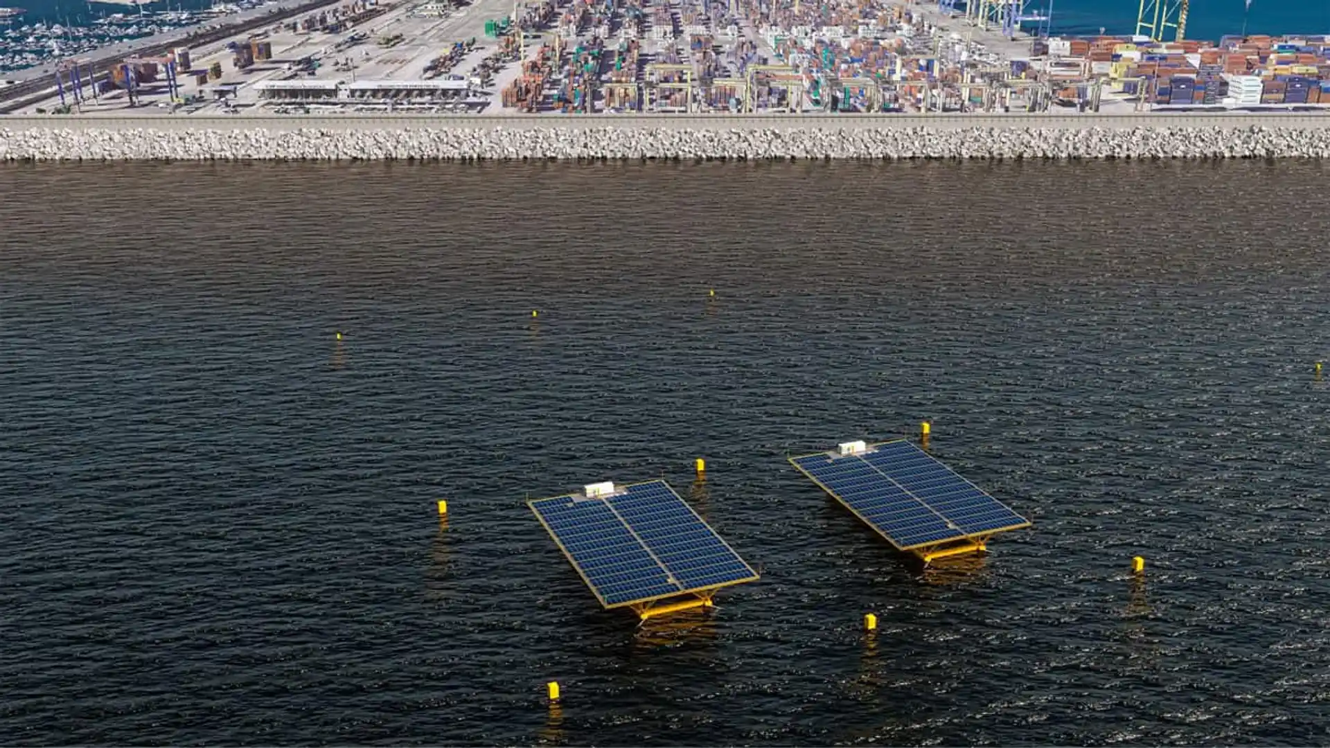 Dos plataformas de paneles solares flotantes instaladas frente al puerto, con la terminal de contenedores al fondo.