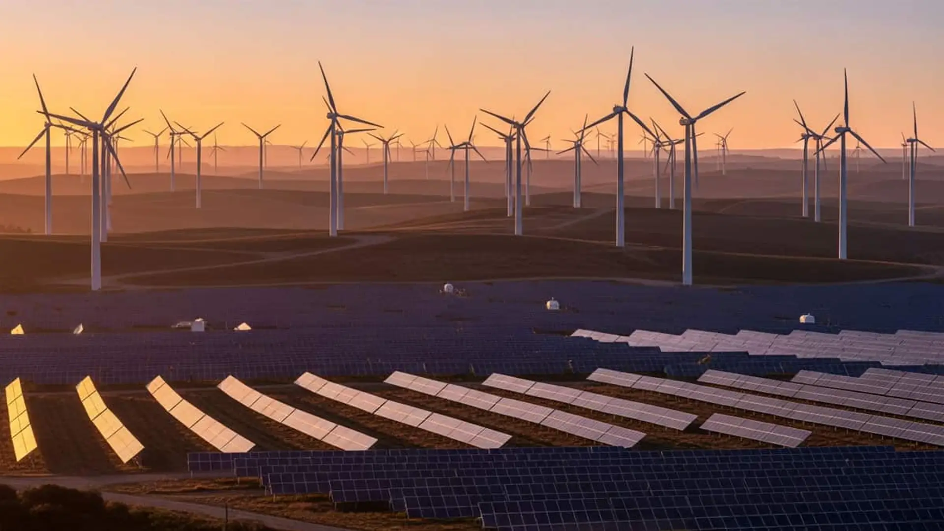Parque eólico y solar combinado al atardecer con filas de paneles y aerogeneradores.