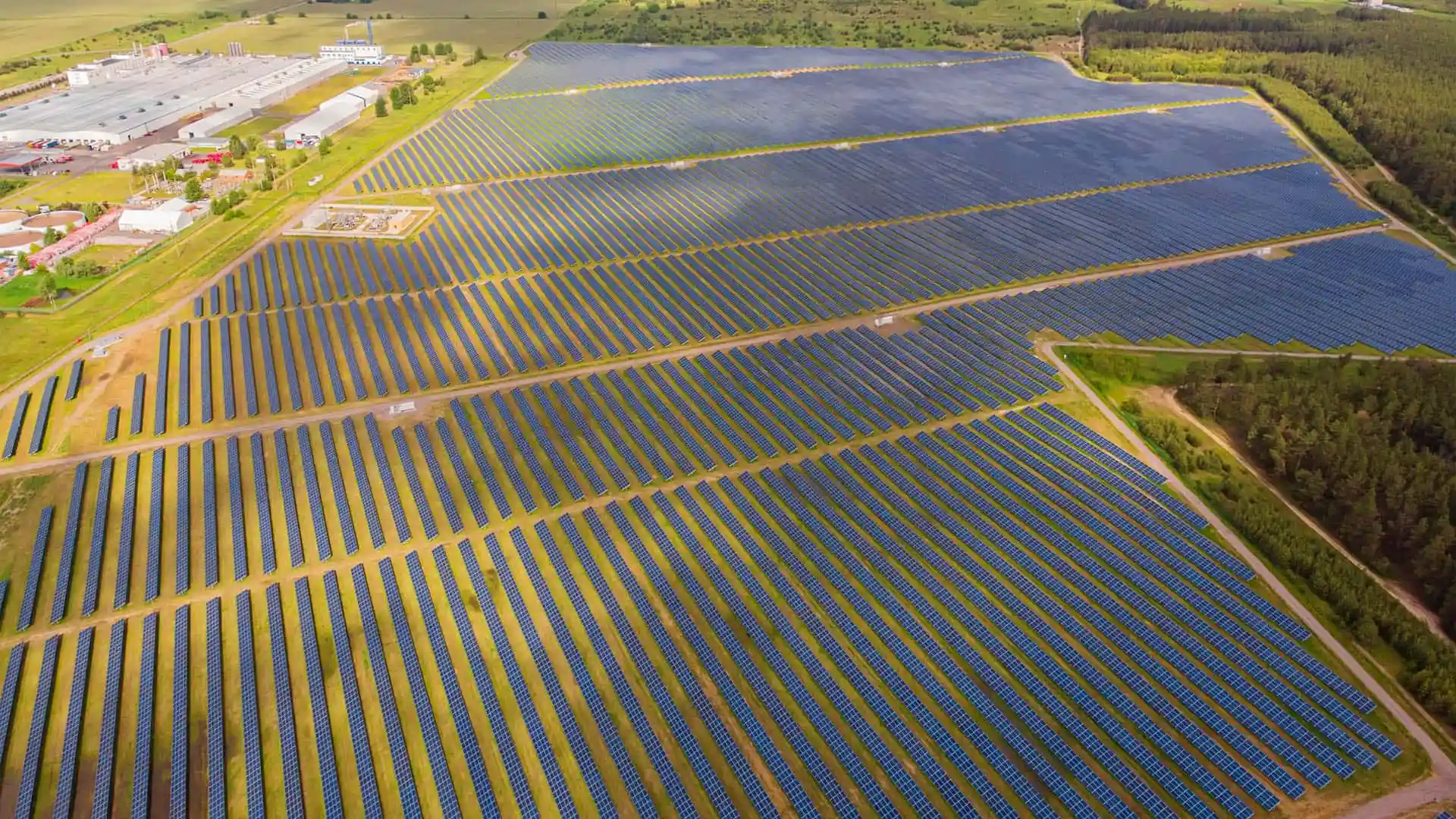 Vista aérea de una gran planta solar fotovoltaica con cientos de paneles alineados.