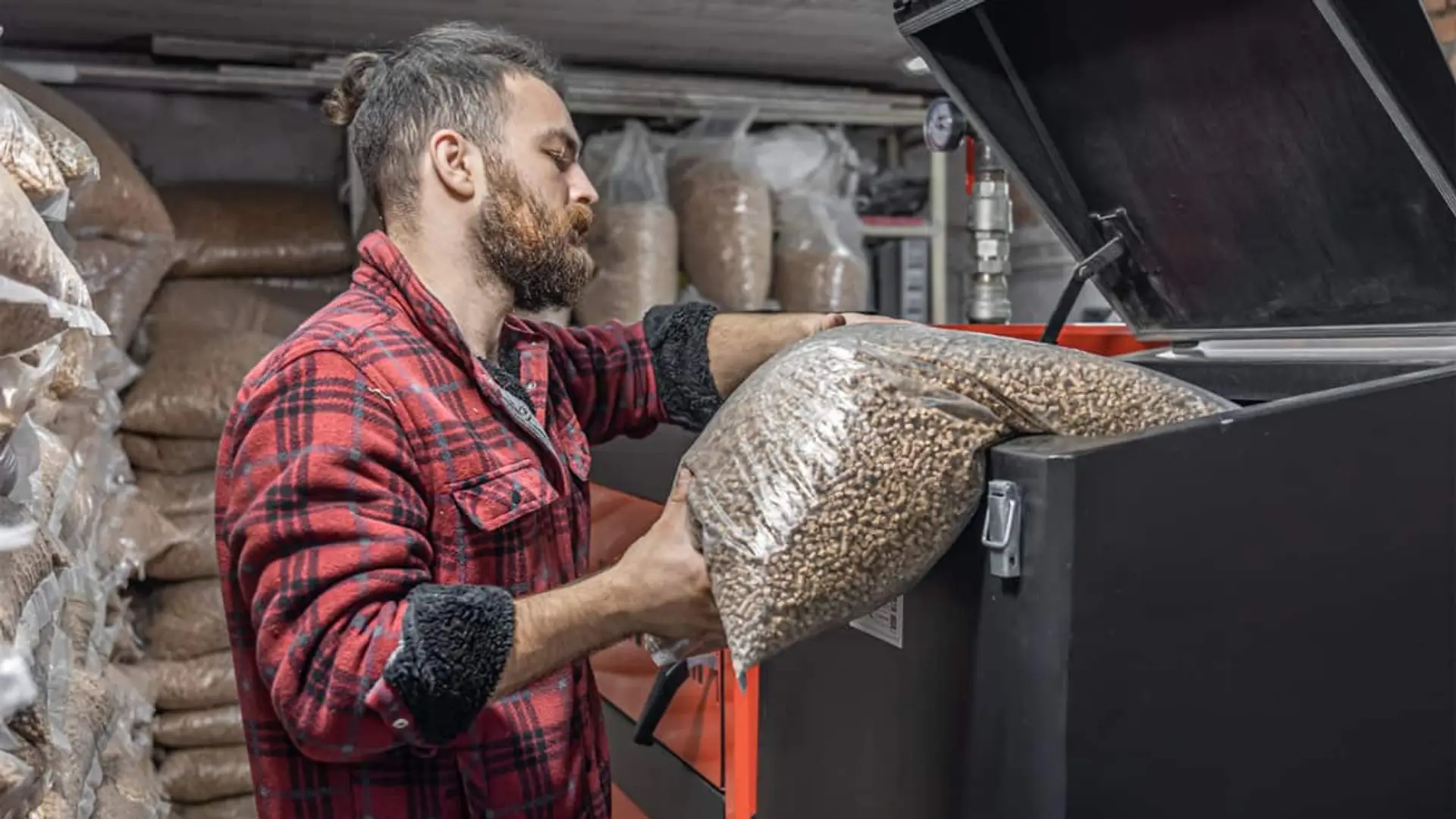 Persona cargando pellets en una caldera en una sala de almacenamiento