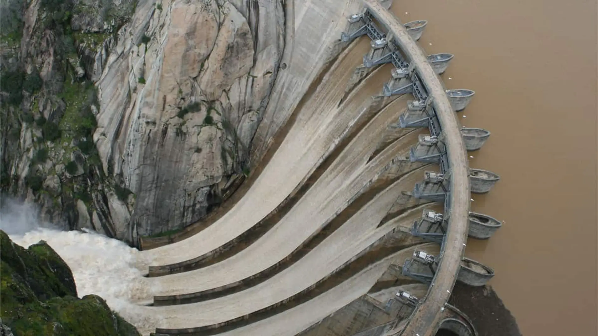 Vista aérea de la presa de Aldeadávila con los aliviaderos abiertos y el embalse a ambos lados.