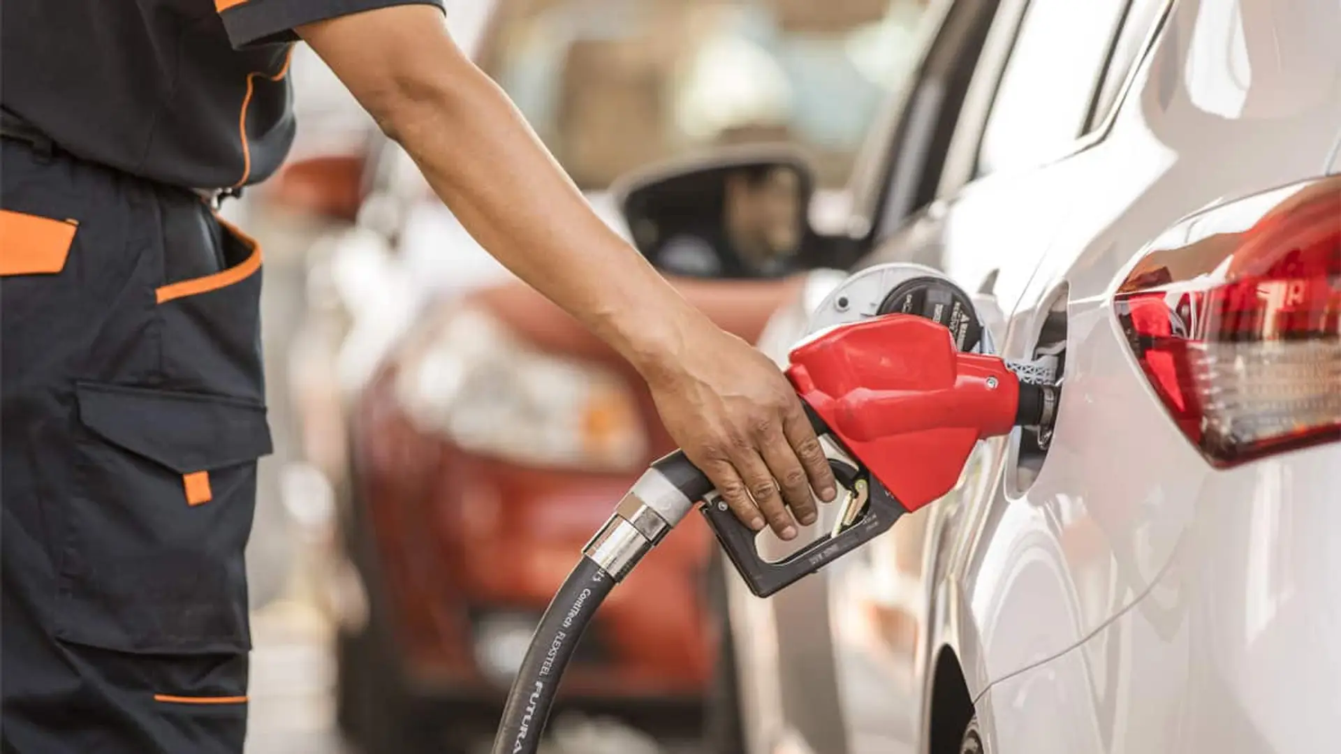Operario repostando gasolina en un coche blanco en una estación de servicio