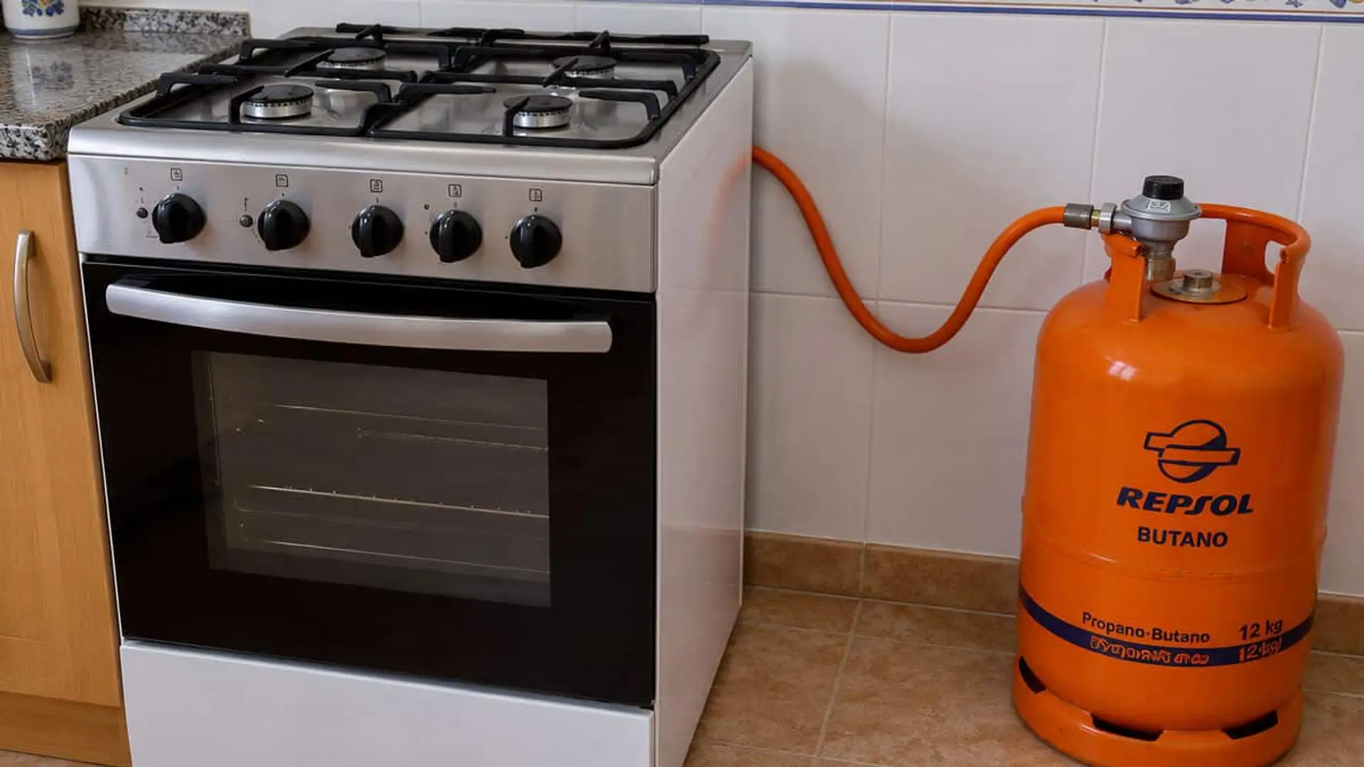 Bombona de butano de Repsol conectada mediante una manguera a una cocina de gas