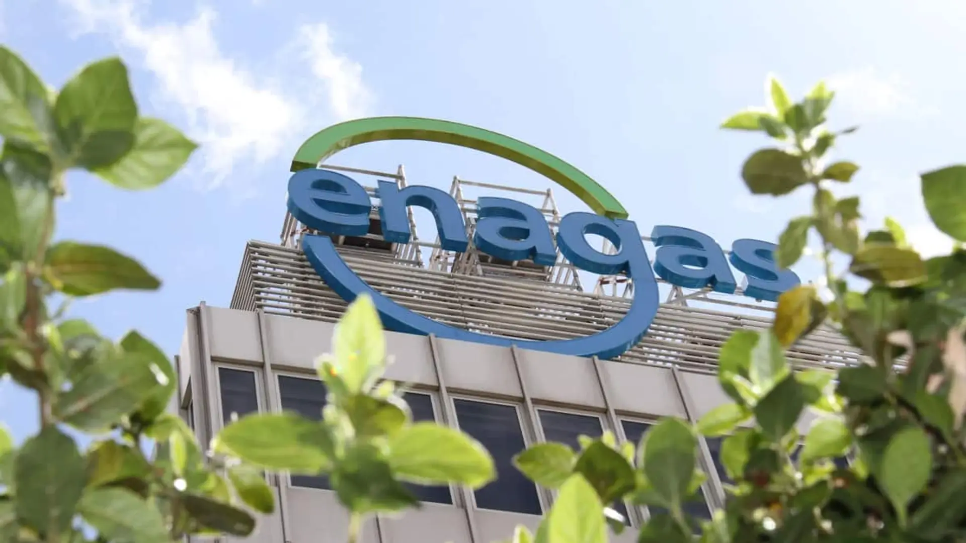 Fachada de un edificio con el logotipo de Enagás visible entre hojas verdes.