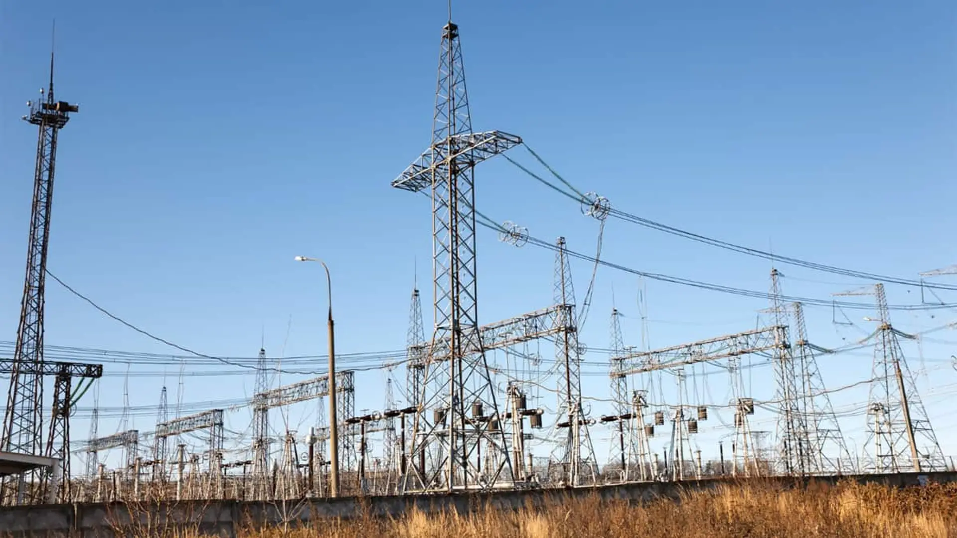 Subestación eléctrica con múltiples torres y cableado de alta tensión en campo abierto.