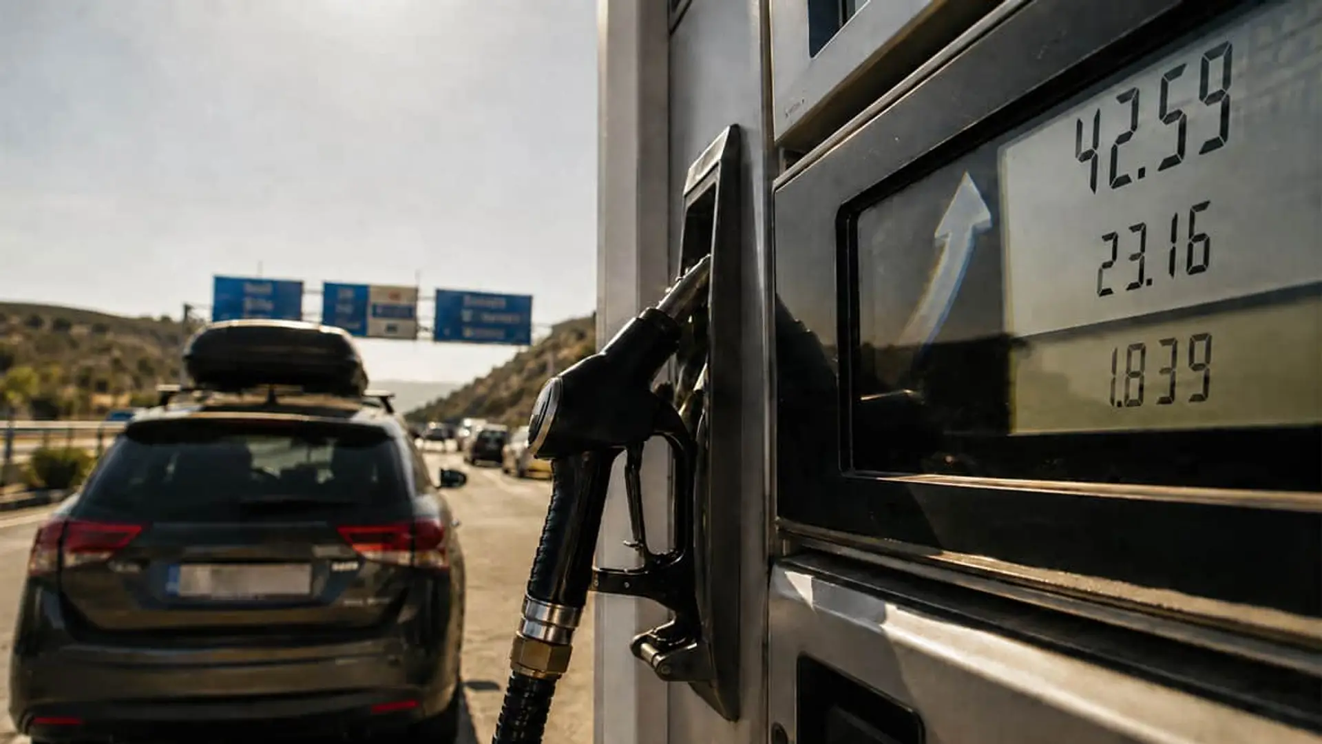 Llenar el depósito ya cuesta 3,30 euros más: así ha subido la gasolina y el diésel en agosto Surtidor de gasolina junto a coche en carretera, reflejando el coste del combustible durante un viaje.