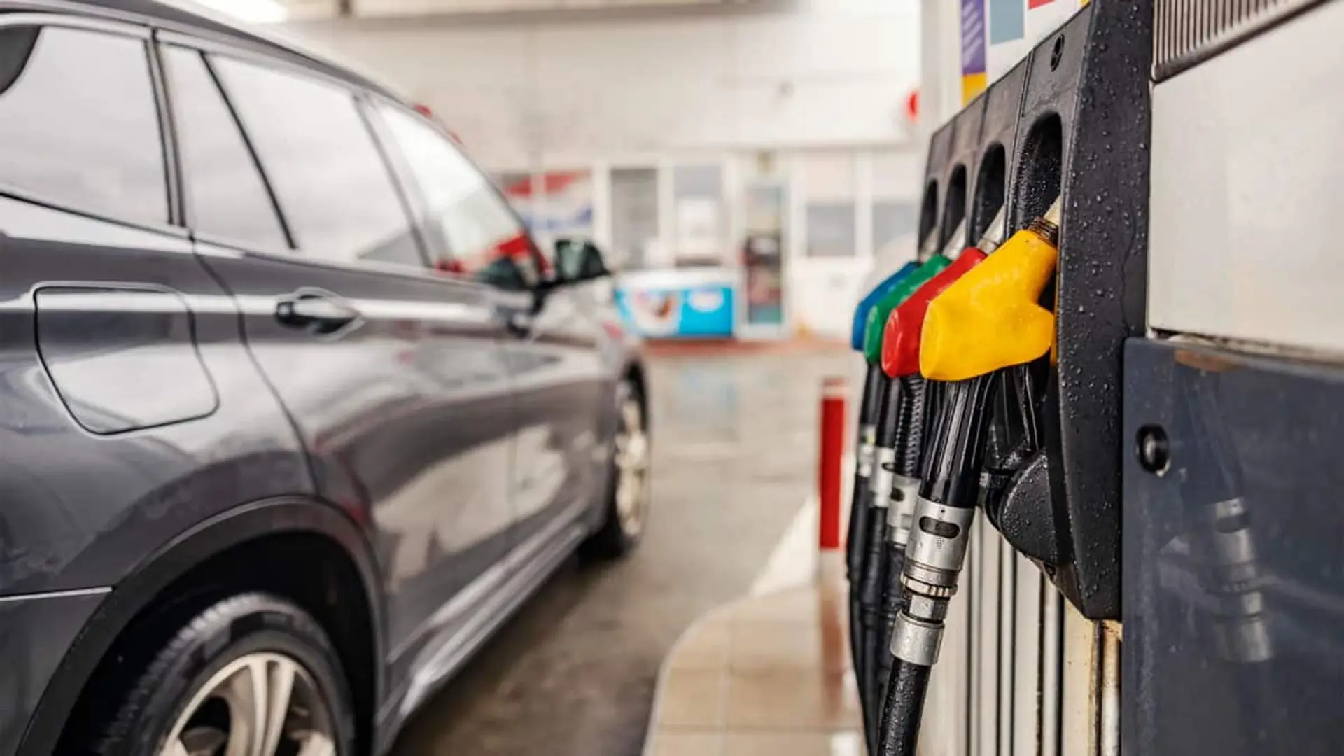 Surtidores de gasolina en una estación de servicio junto a un coche preparado para repostar combustible.