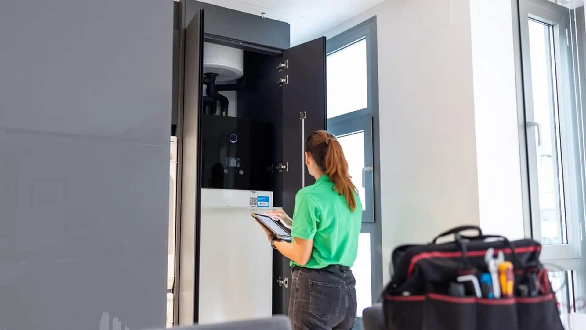 Técnica revisando un equipo de aerotermia instalado en el interior de una vivienda