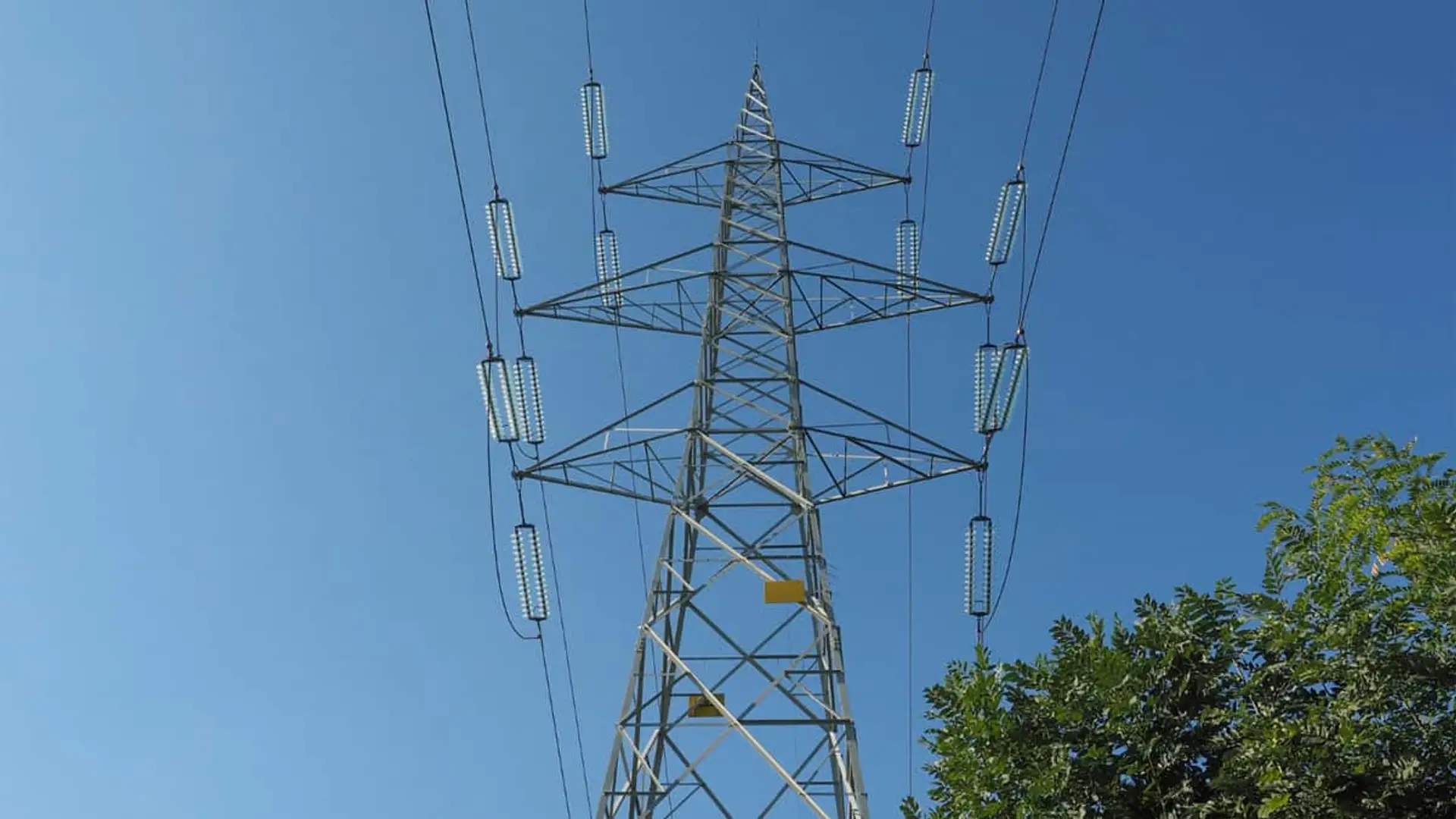 Torre eléctrica de alta tensión vista desde abajo contra un cielo azul
