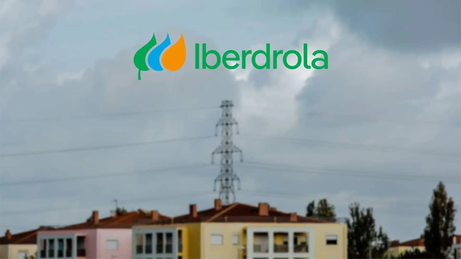 Torre eléctrica sobre varias viviendas desenfocadas con el logotipo de Iberdrola en la parte superior