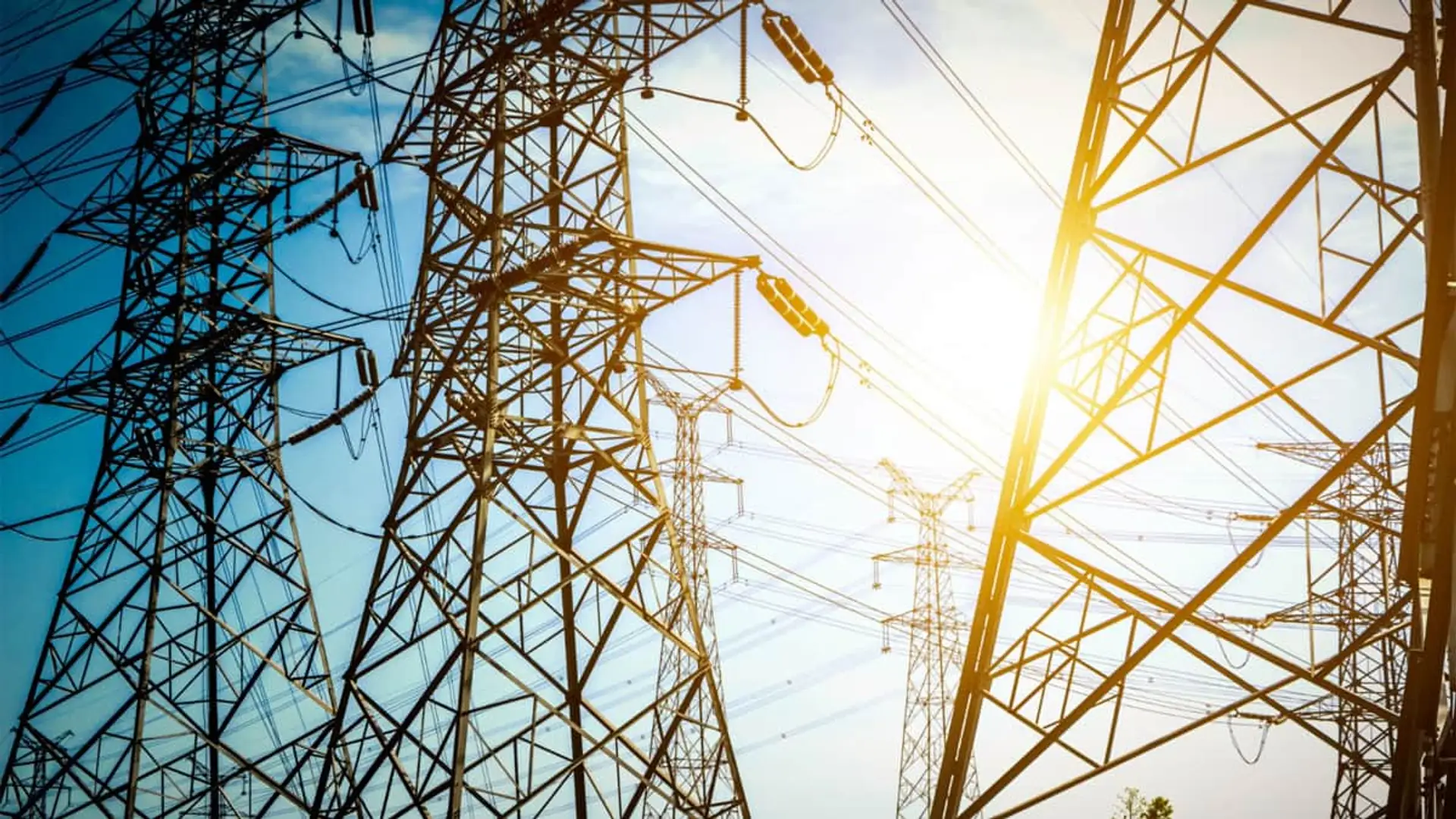 La saturación de la red eléctrica frena la vivienda y la industria: solo se aprueba el 12% de las nuevas conexiones Torres de alta tensión y tendido eléctrico de red de transporte de energía bajo el sol.