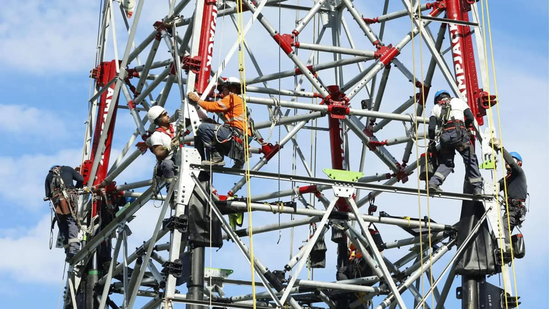 Técnicos realizando trabajos de mantenimiento en una torre eléctrica de alta tensión.