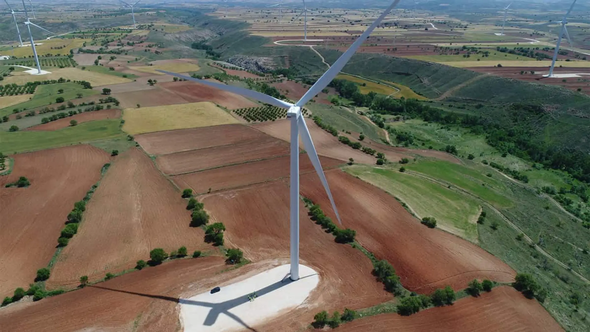 Vista aérea de un parque eólico en Aragón con aerogeneradores instalados sobre terrenos agrícolas y zonas rurales