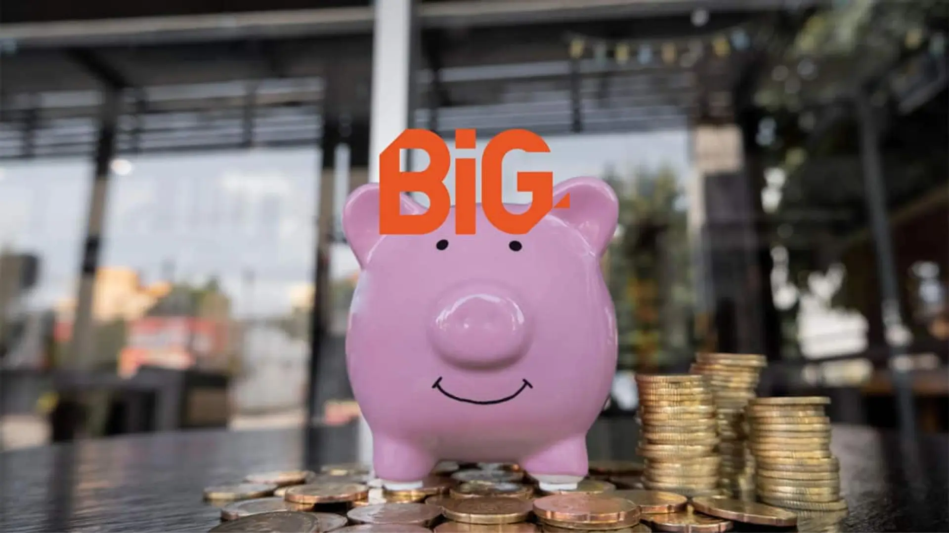 Hucha rosa rodeada de monedas con el logo de BiG, simbolizando el ahorro y las cuentas remuneradas.
