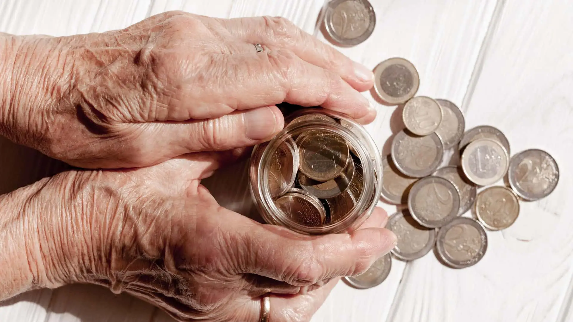 Ahorrar con una pensión cada vez es más complicado: un tercio de los jubilados no lo consigue Manos de una persona mayor con un bote de monedas.