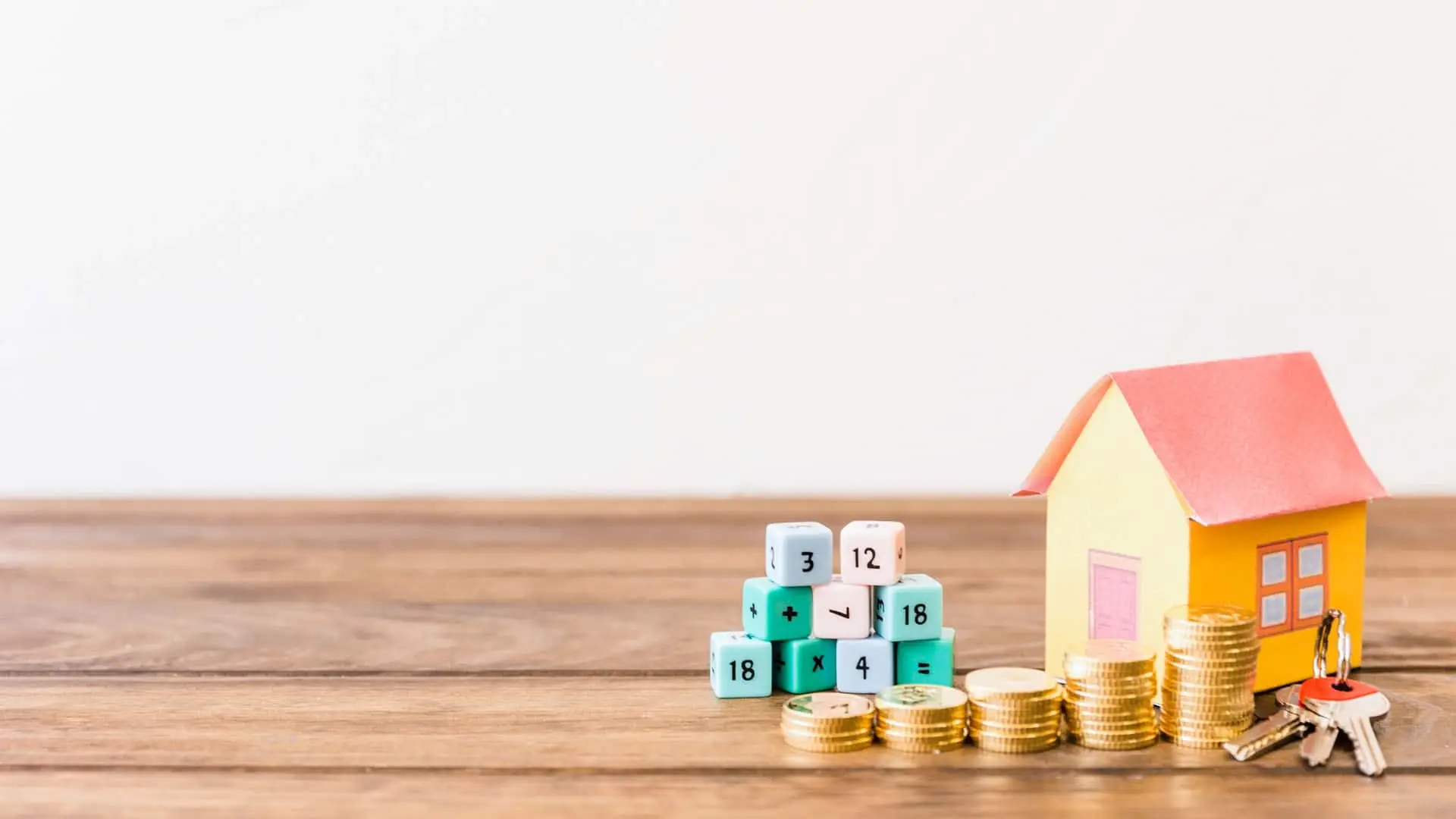 Casa, monedas y cubos de cálculo para planificar el coste de una hipoteca y el ahorro.
