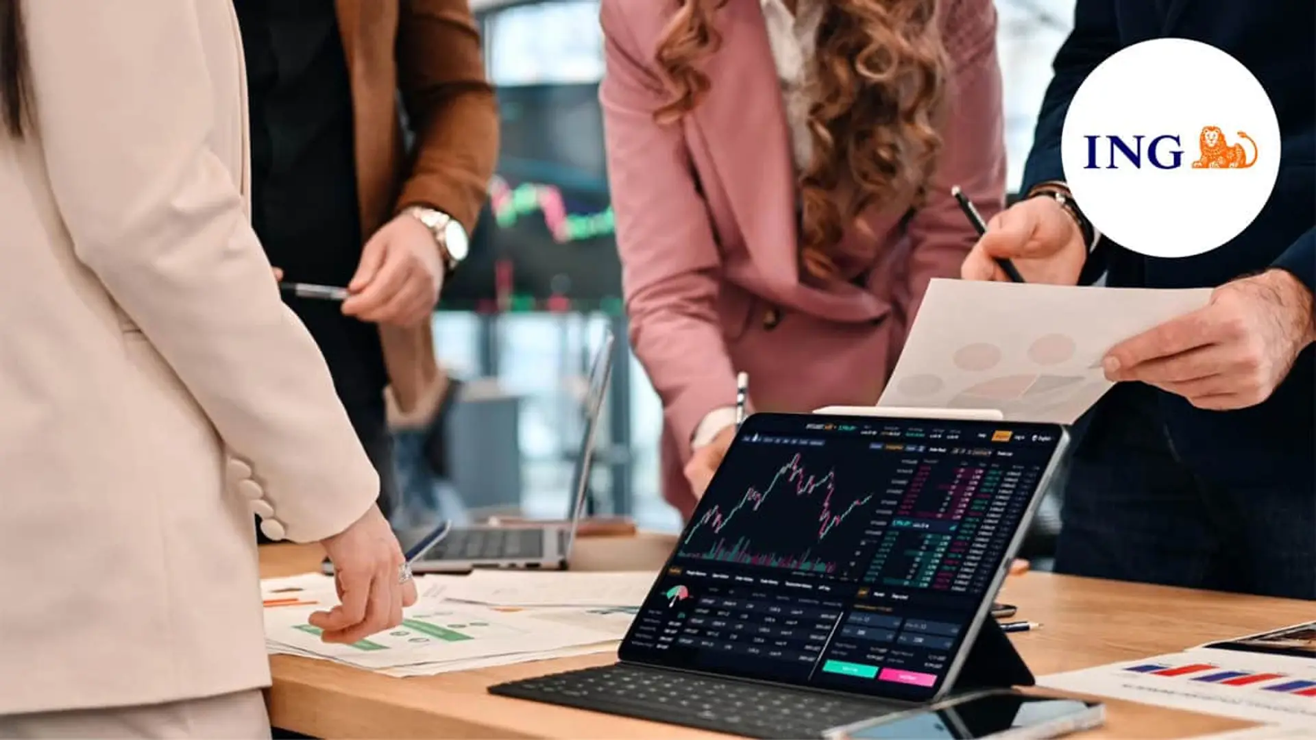 Equipo financiero analizando gráficas de inversión en una tablet junto al logotipo de ING para banca de inversión.