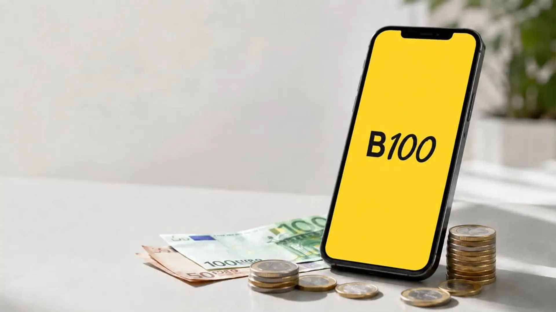 Aplicación B100 en un smartphone junto a billetes y monedas de euro, símbolo de ahorro e inversión digital.