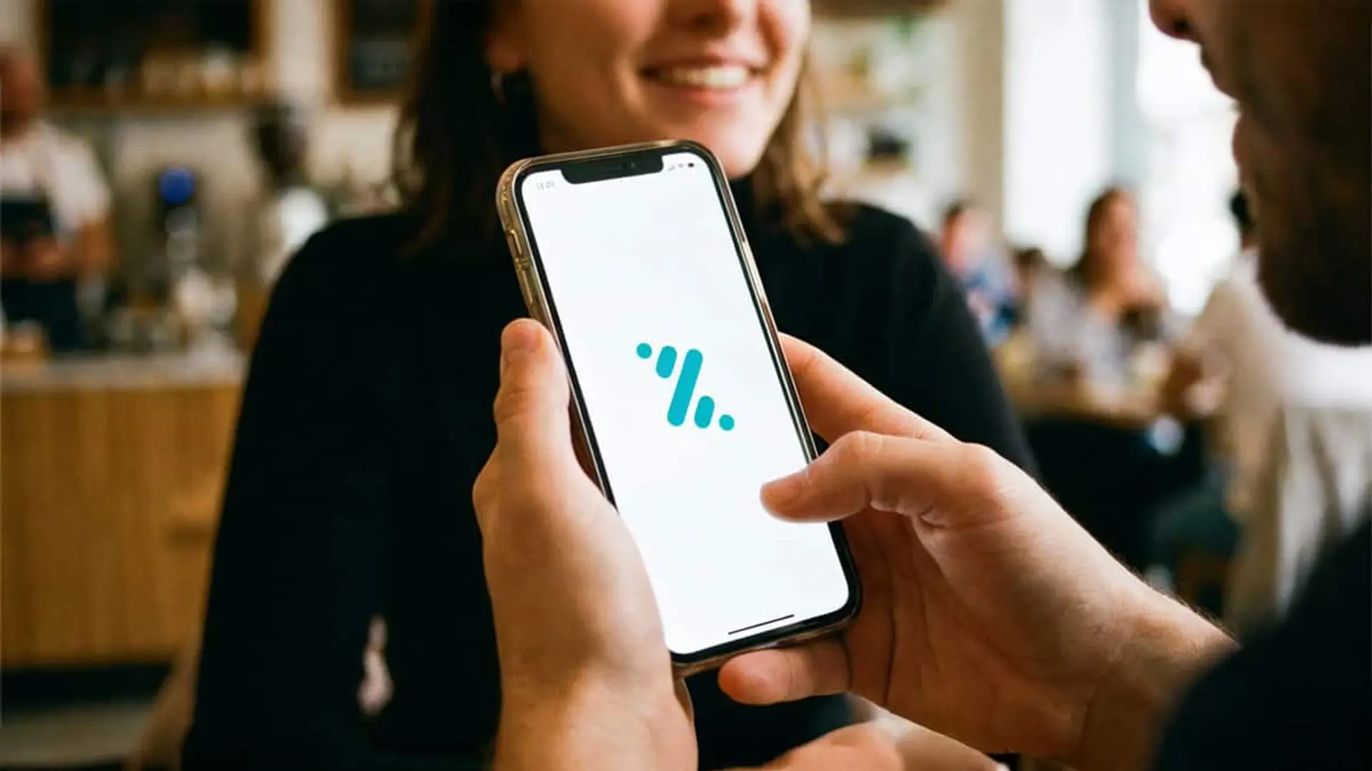 Usuario mostrando una aplicación de pagos móviles en su teléfono durante una transacción en un bar.