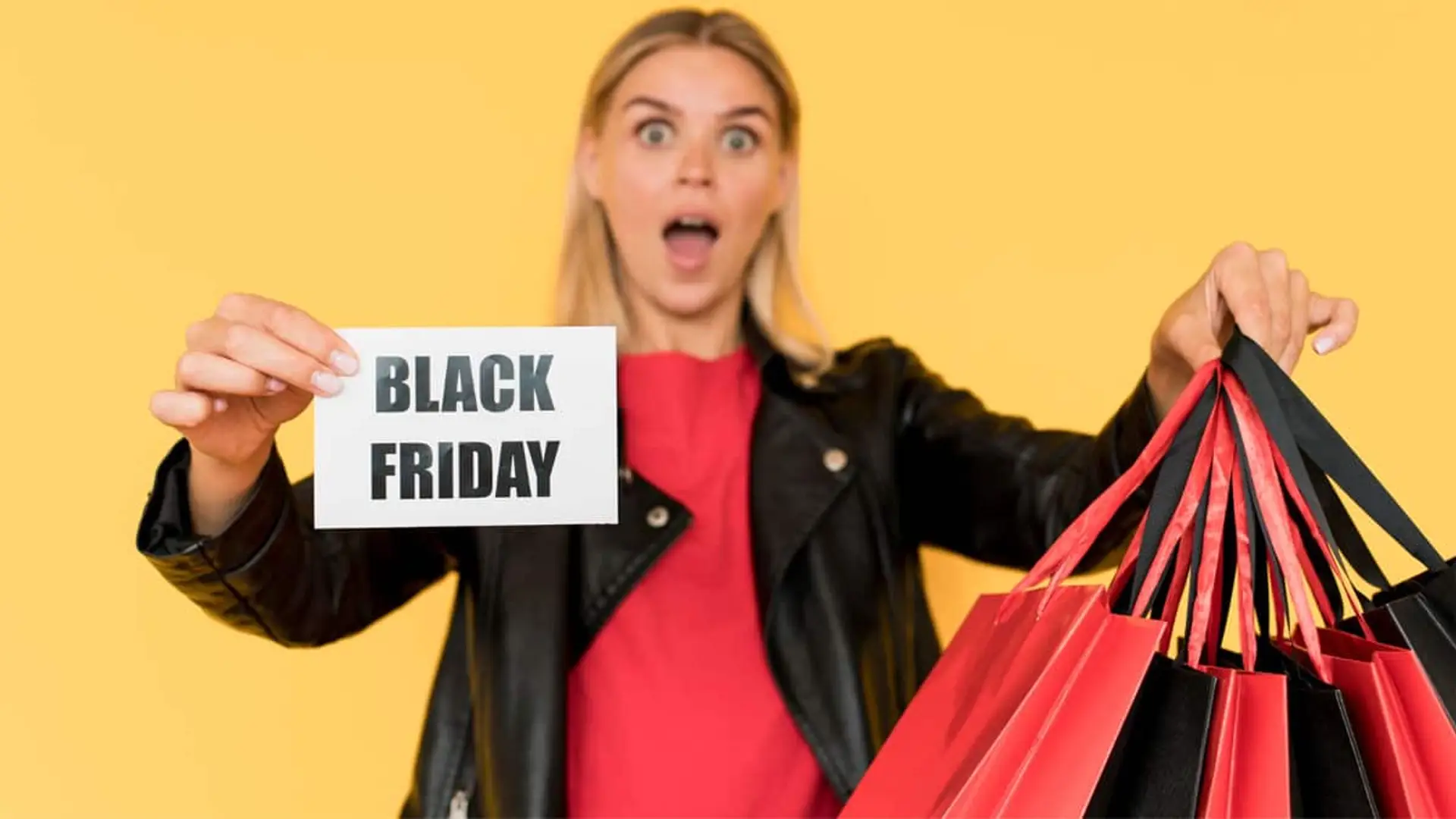 Mujer sorprendida mostrando un cartel de Black Friday y varias bolsas de compra.