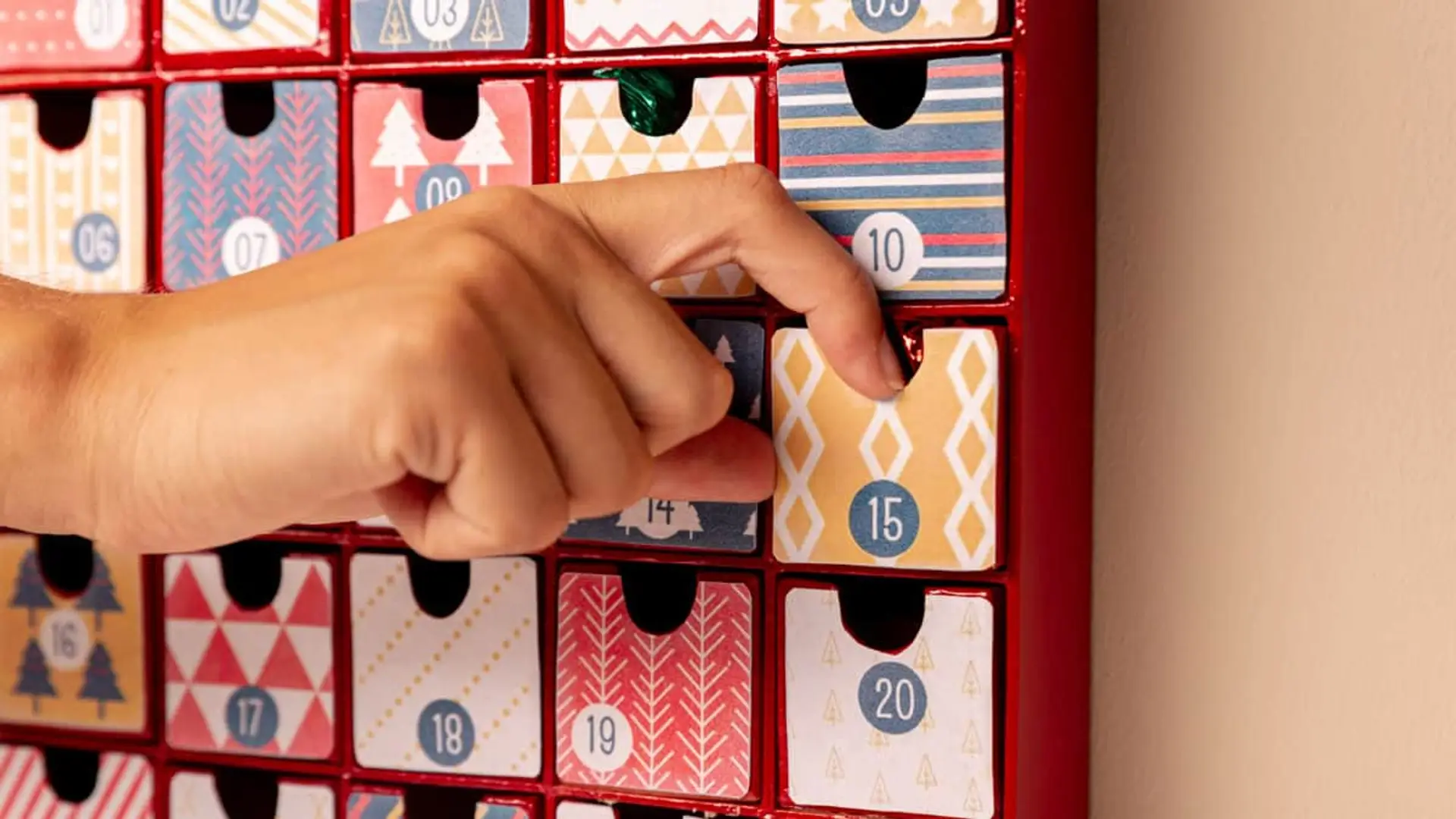 Mano abriendo cajón de calendario de adviento reutilizable rojo en la cuenta atrás para Navidad.
