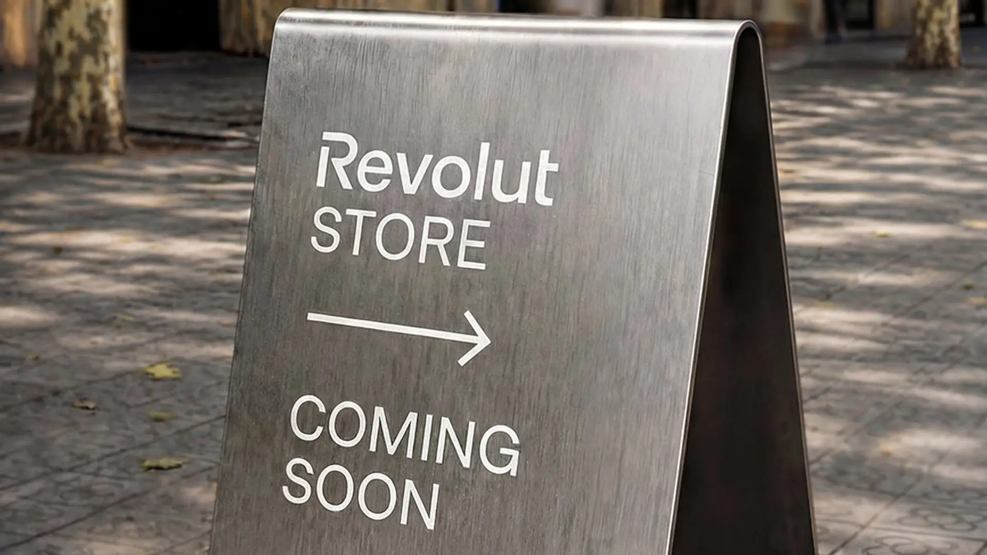 Cartel metálico con el texto Revolut Store y Coming Soon con una flecha hacia la derecha