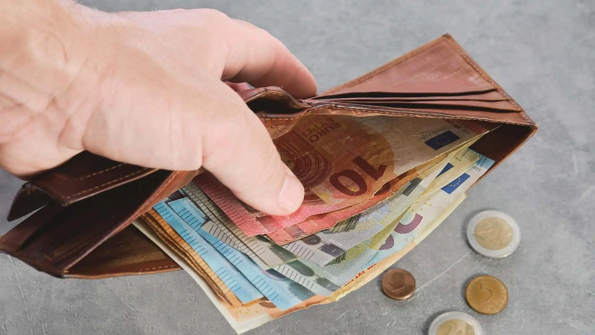 El BCE recuerda la importancia del efectivo: esta es la cantidad que deberías tener siempre a mano Mano abriendo una cartera con billetes y monedas de euro.