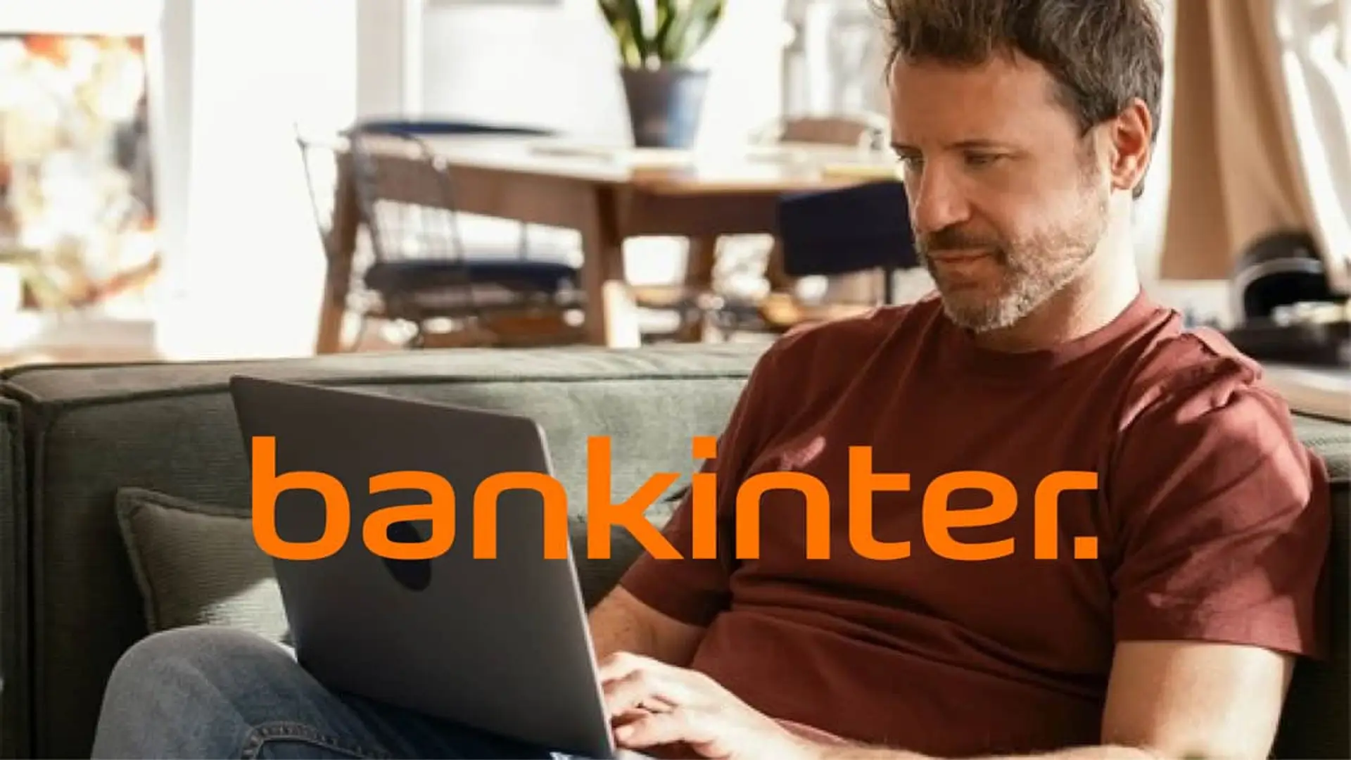 Usuario gestionando su banca online de Bankinter desde un ordenador portátil en el salón de su casa.