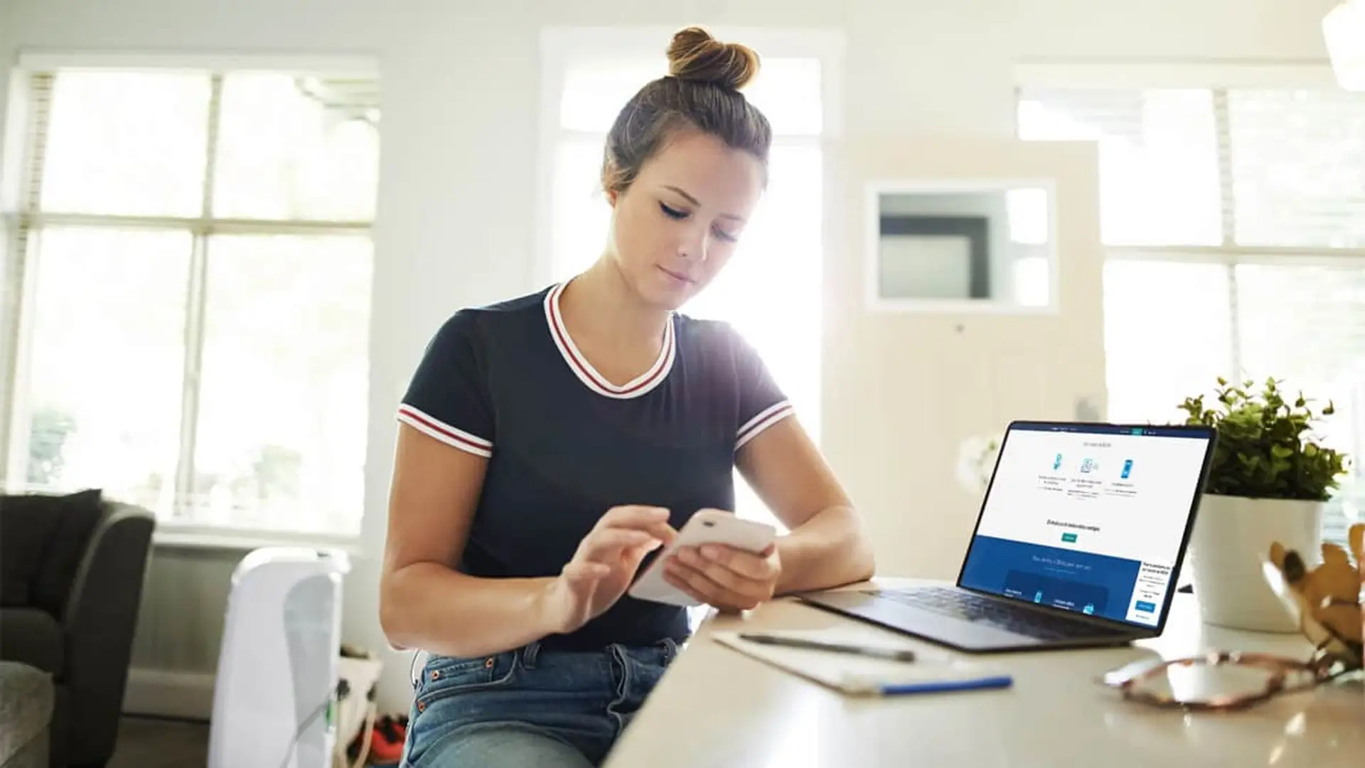 Los jóvenes eligen BBVA: las altas digitales crecen un 46% en un año Clienta utilizando la banca online en su portátil y la app móvil para gestionar sus finanzas personales desde casa.