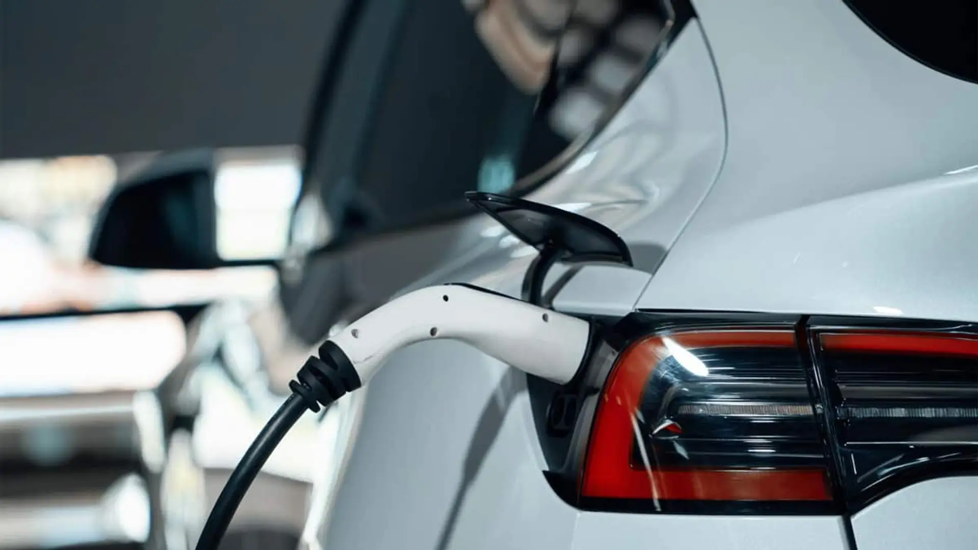 Coche eléctrico blanco conectado a un cargador en la parte trasera