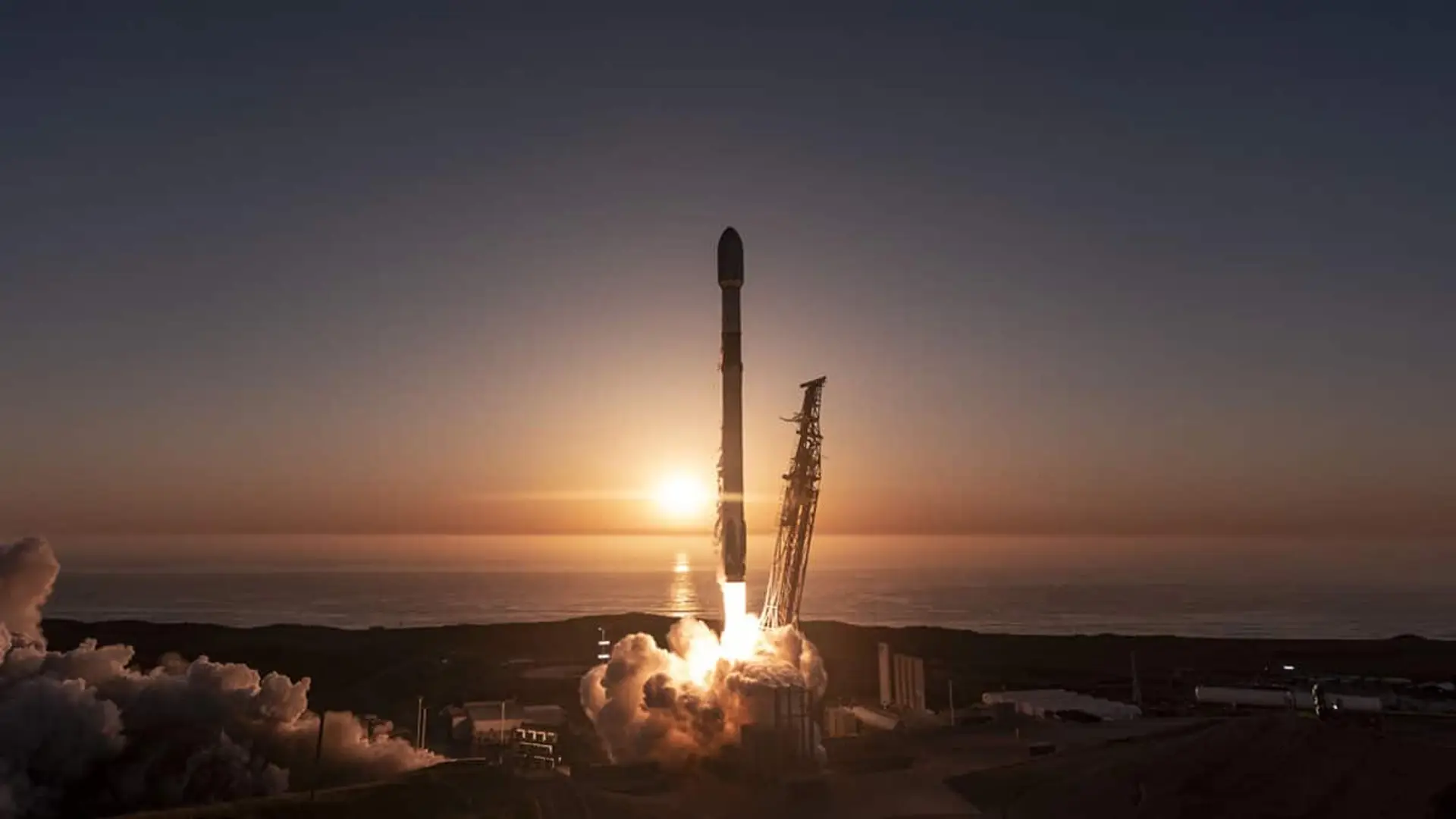 Cohete de SpaceX despegando al amanecer desde una base de lanzamiento junto al mar